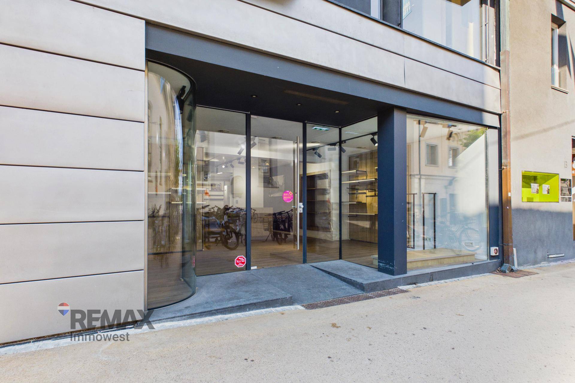 Eingangsbereich eines Geschäfts mit großer Glasfront, Schaufenstern und einer Rampe.