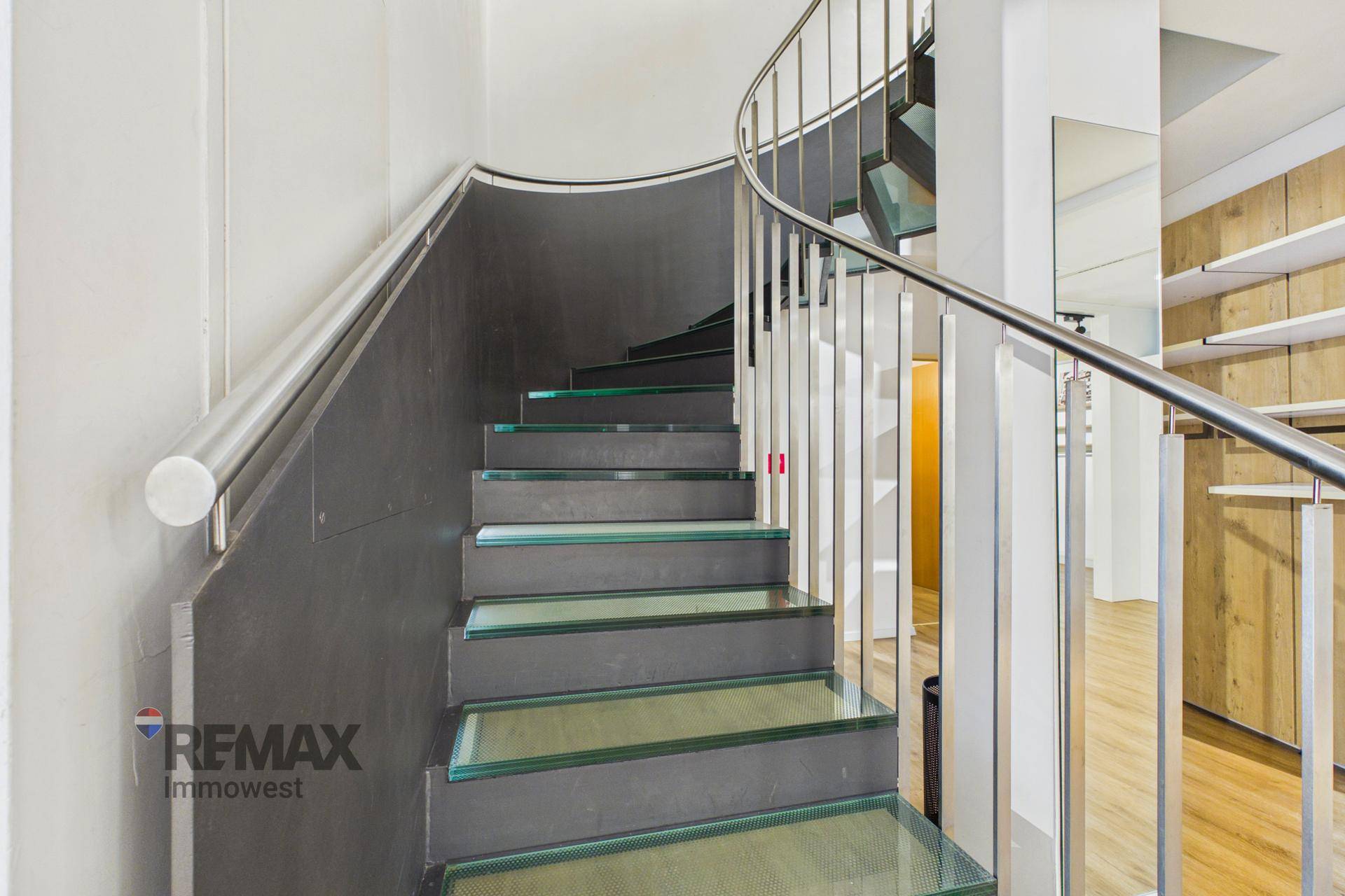 Moderne Treppe mit Glasstufen und Edelstahlgeländer, die in den oberen Bereich führt.
