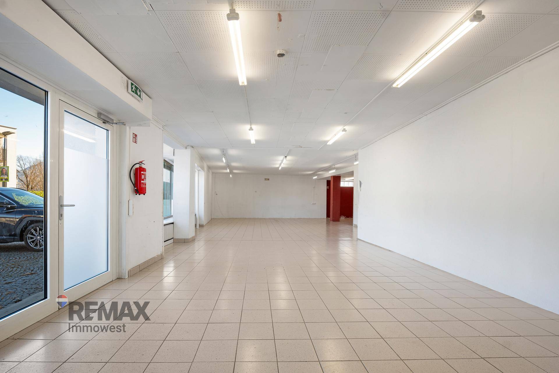 Weitläufiger Geschäftsraum mit großen Fenstern und Fliesenboden, der viel Tageslicht hereinlässt.
