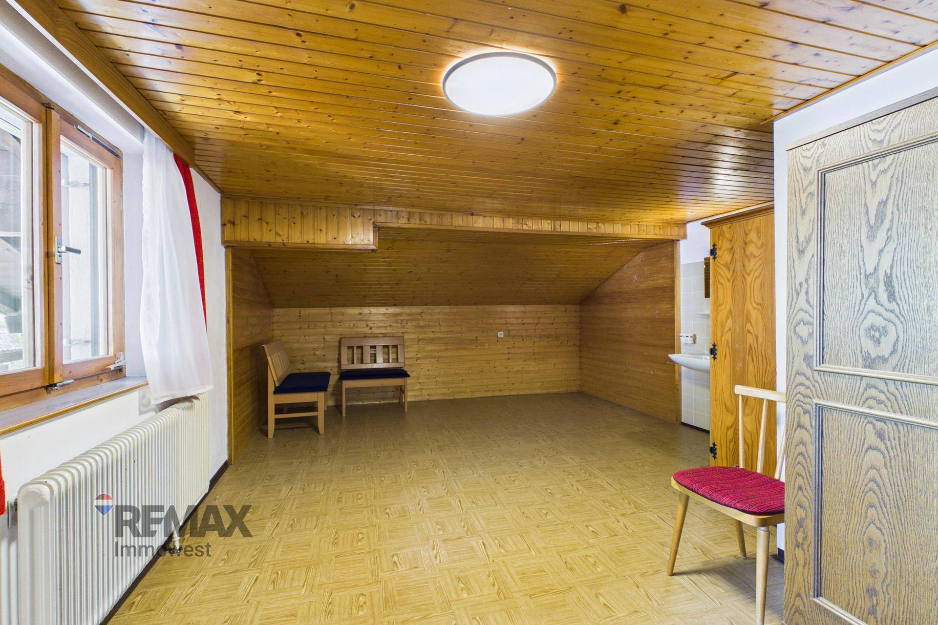 Dachzimmer mit Holzdecke, gemustertem Boden und schräger Wand, ideal als Gästezimmer.