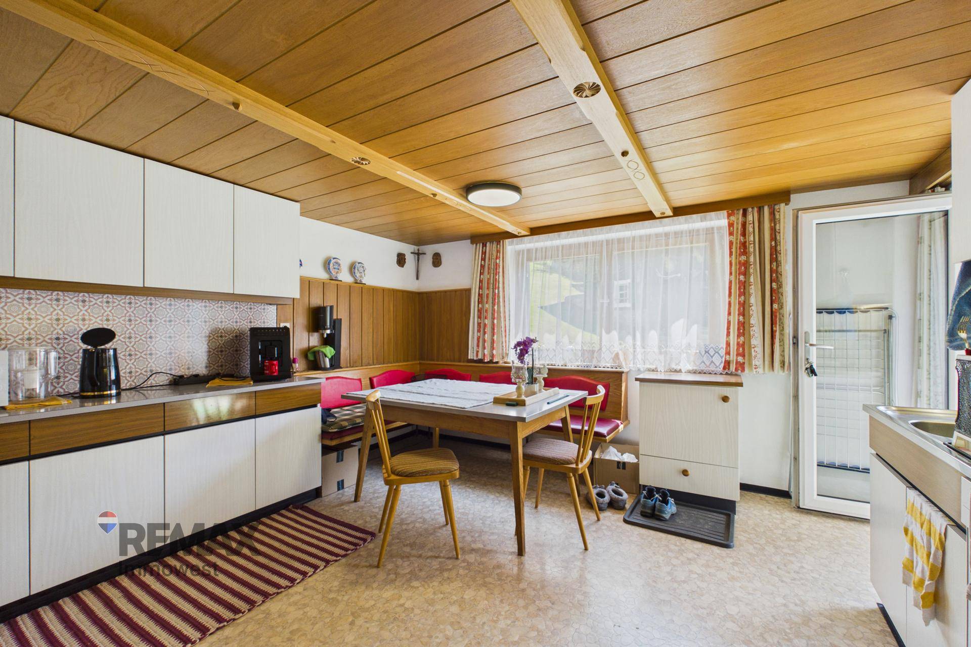 Traditionelle Küche mit weißen Schränken, Essbereich und Fenster, im Landhausstil.