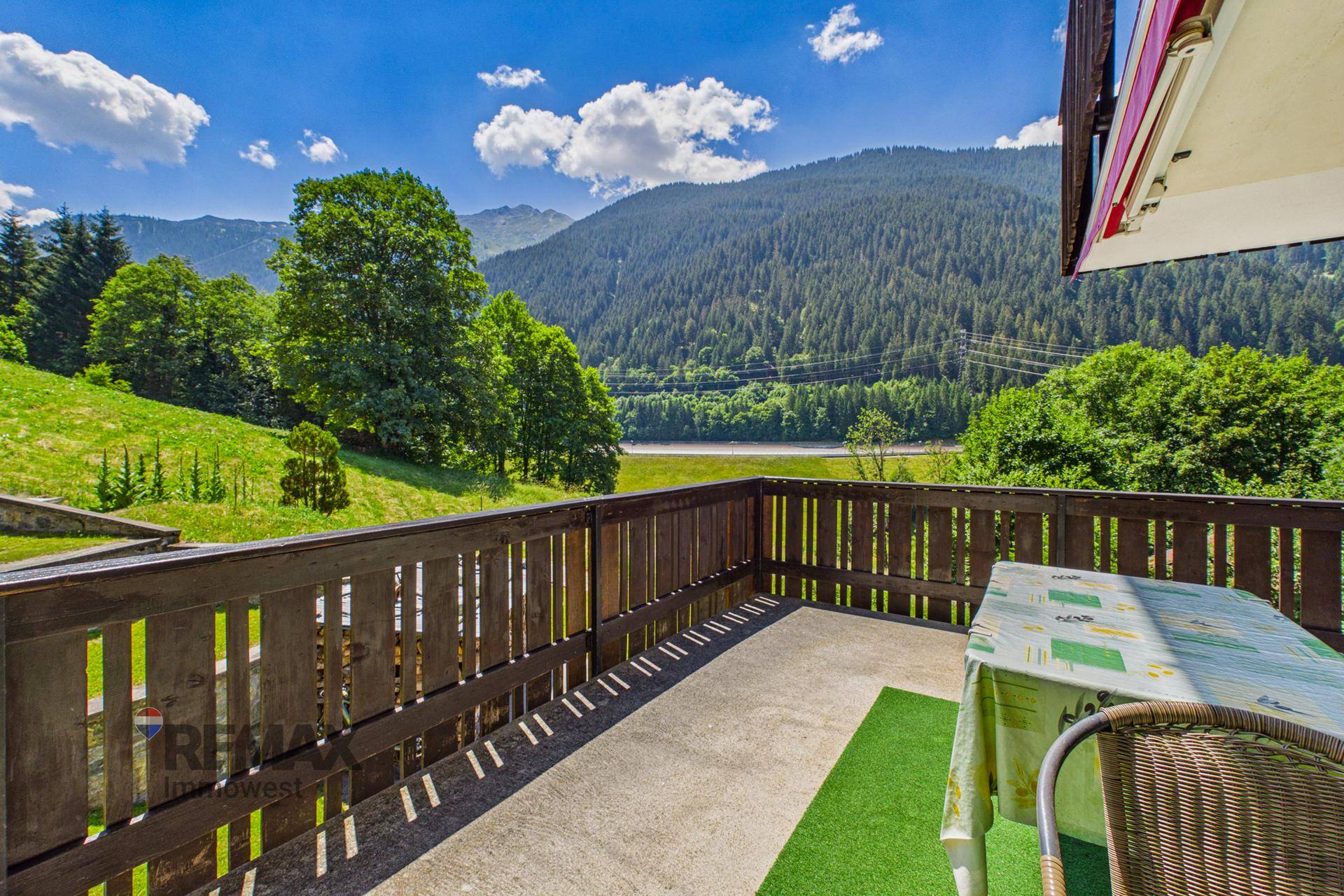 Geräumiger Balkon mit Sitzgelegenheiten und atemberaubendem Panoramablick auf See und Berge.