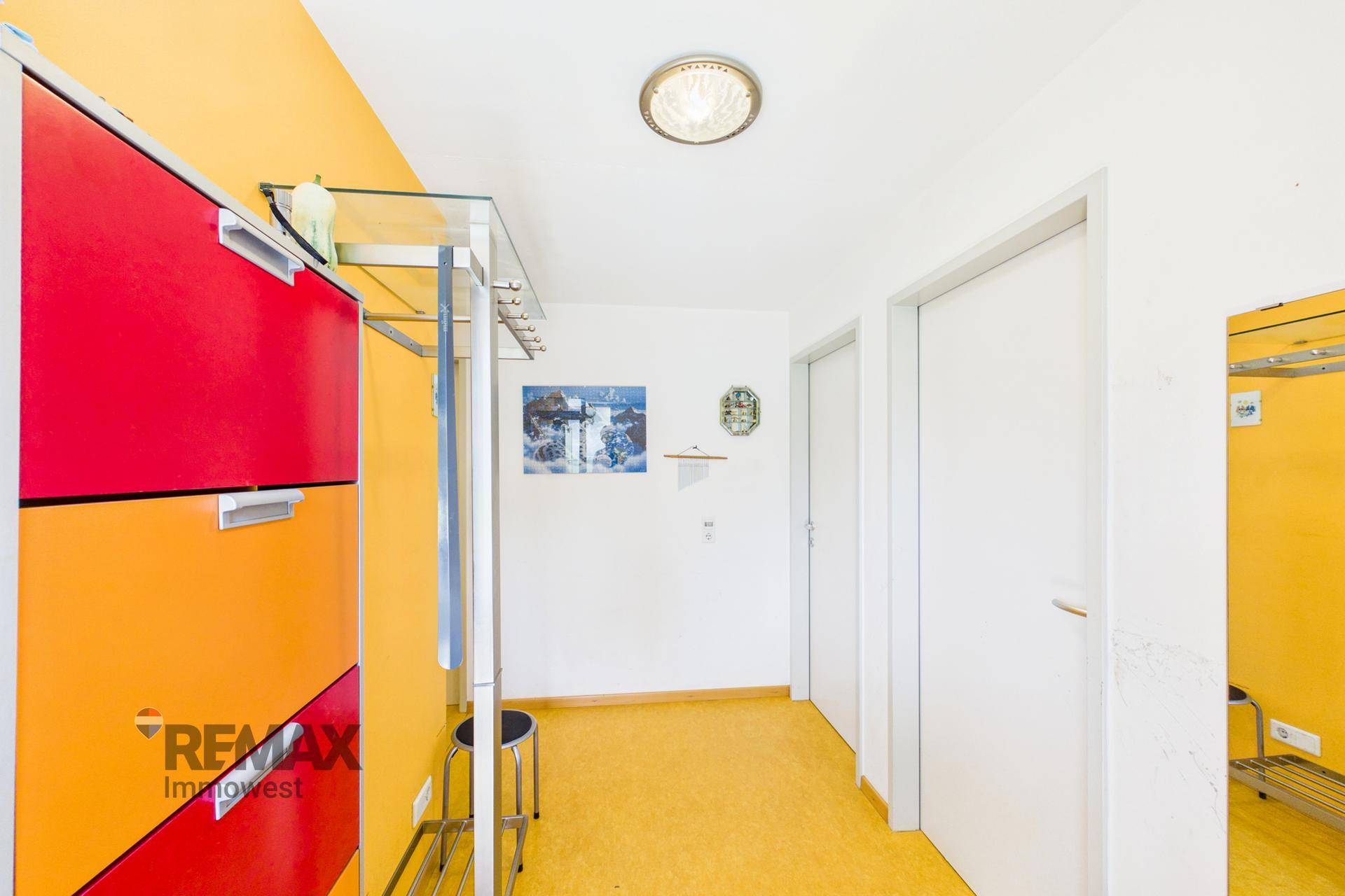 Flur mit farbenfrohem Schuhschrank, gelber Wand und Zugang zu weiteren Räumen der Wohnung.