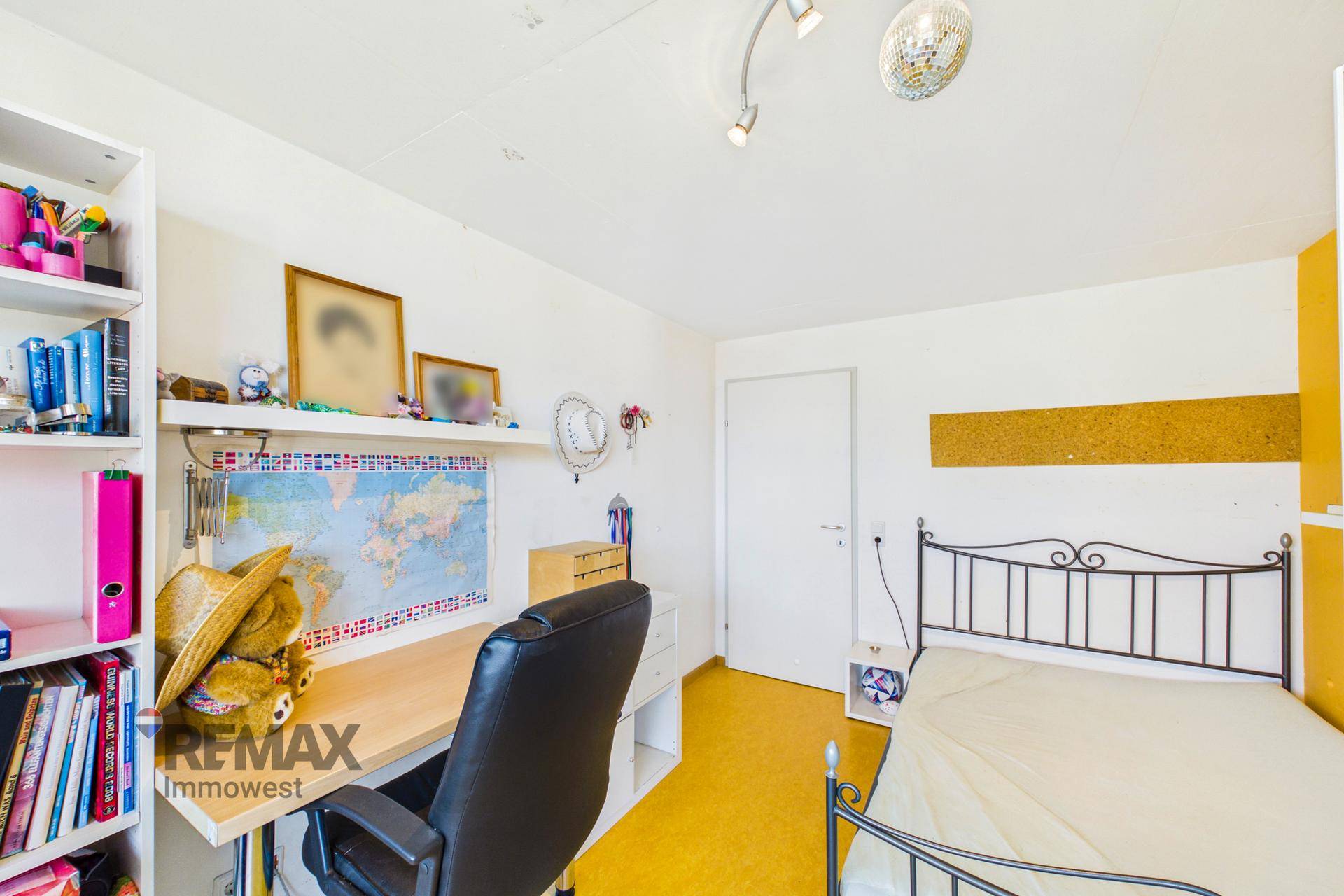 Kinderzimmer mit Schreibtisch, Regal und gelbem Bodenbelag, ideal zum Lernen und Spielen.