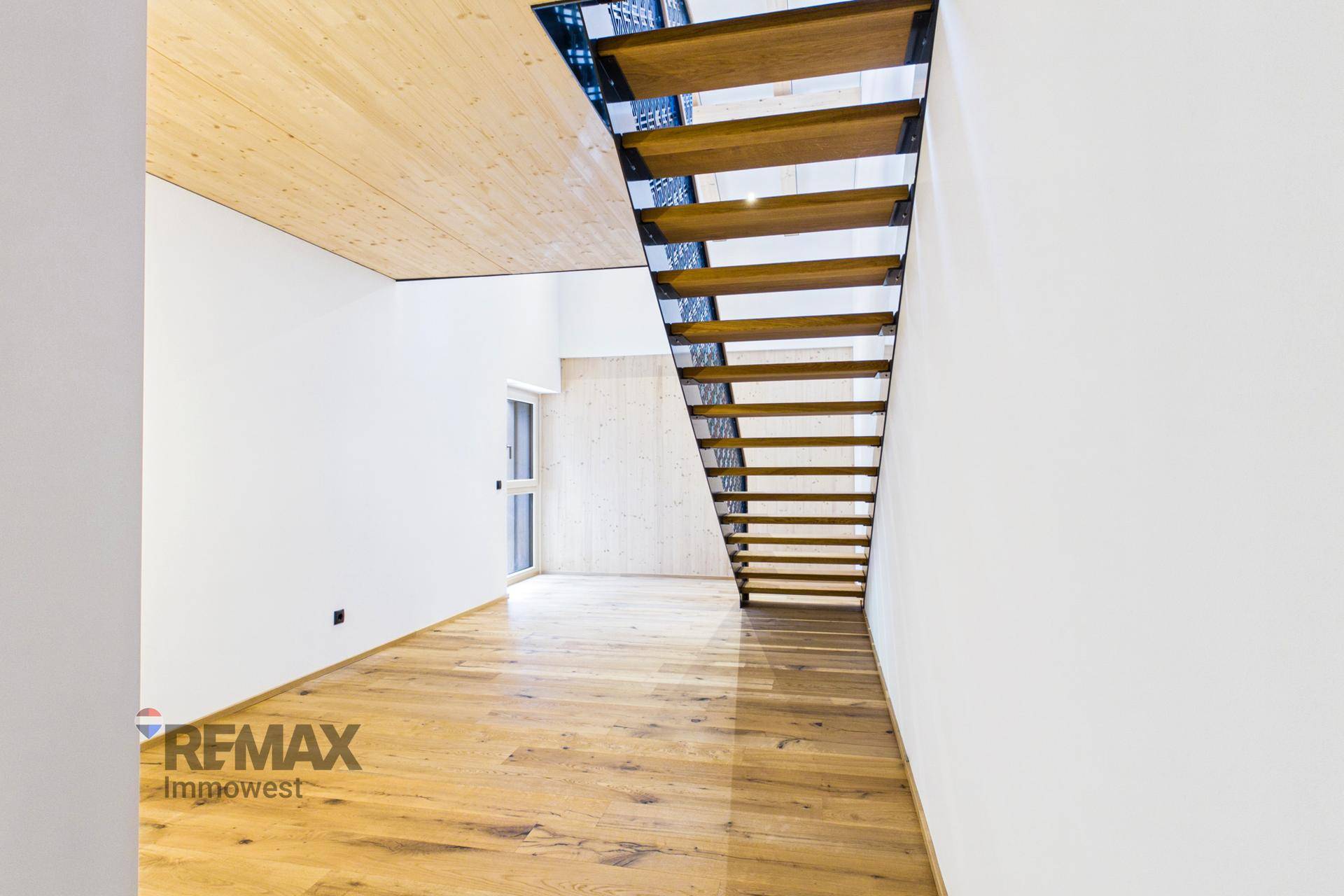 Geräumiger, heller Raum mit Holztreppe und Eichenparkett, bereit für die Einrichtung.
