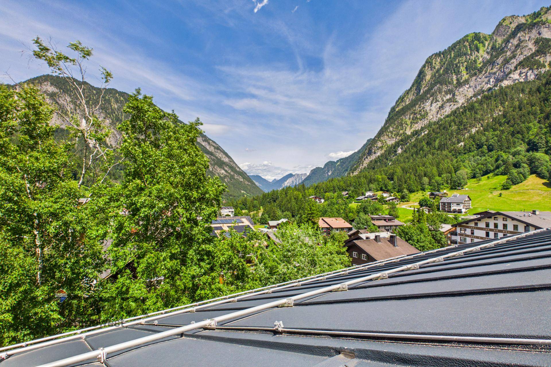 Panoramablick über das Tal und die umliegenden Berge von einem Dachbereich aus.