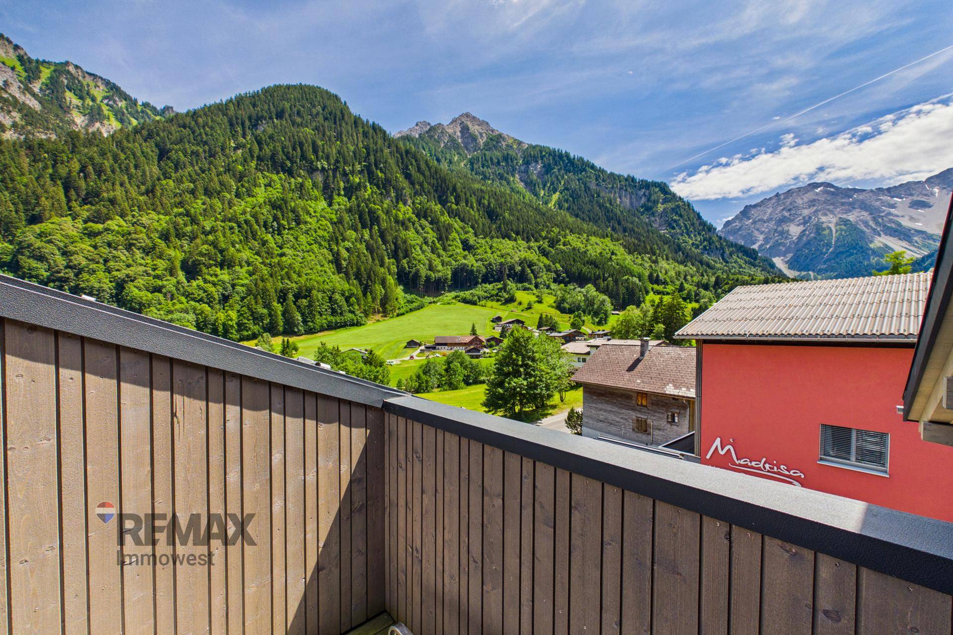 Kleiner Balkon mit Holzwänden und weitem Blick auf die grünen Berge und das Tal.