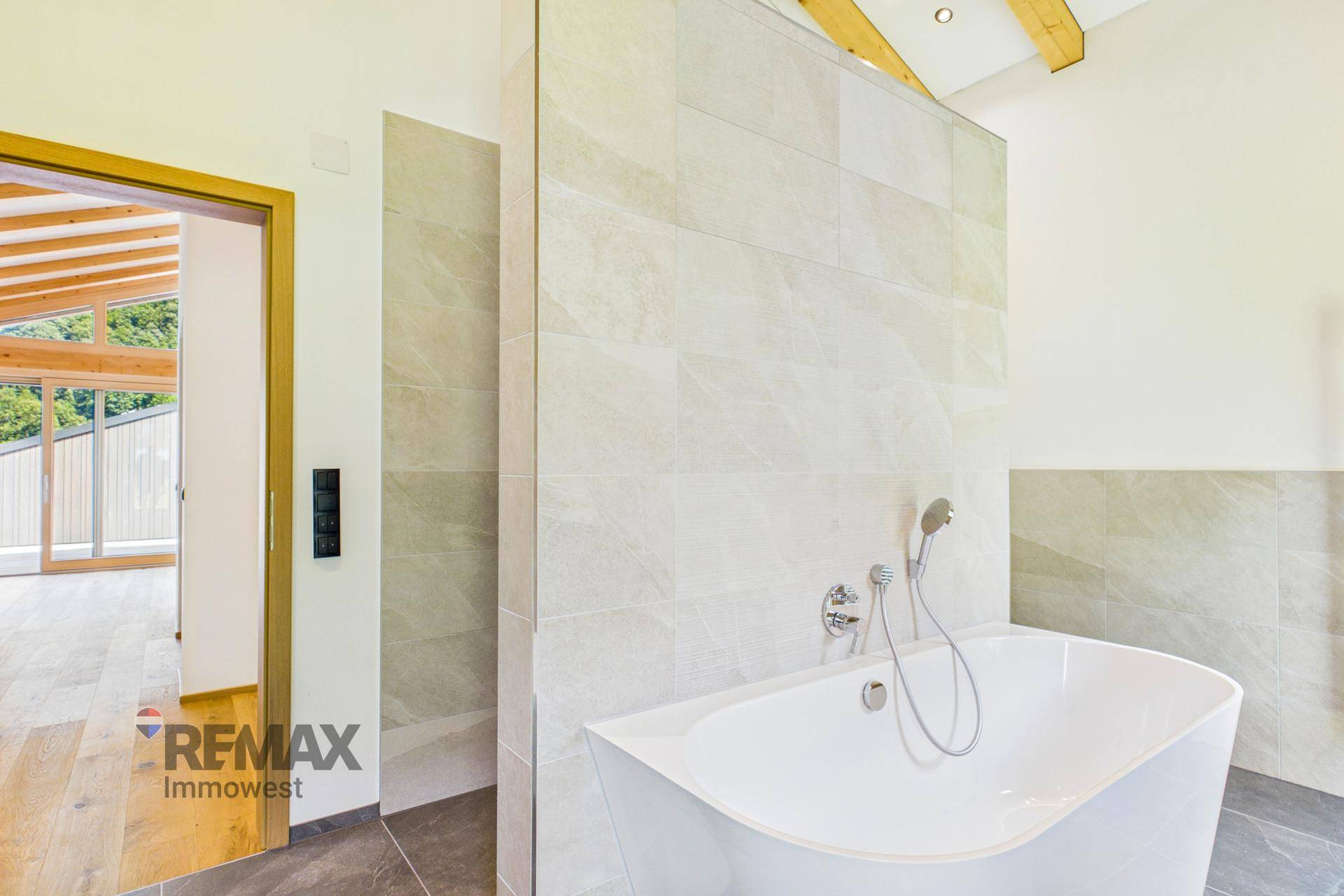 Elegantes Badezimmer mit moderner Badewanne und Blick in den angrenzenden Wohnbereich.
