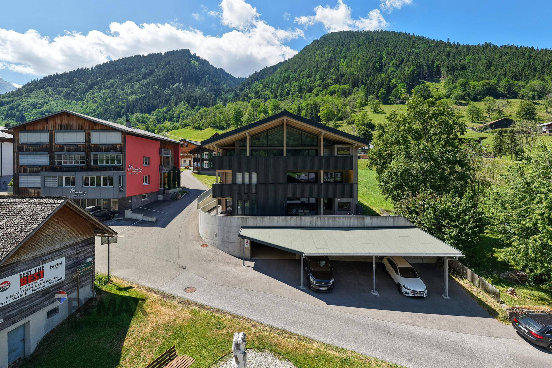 Modernes Wohngebäude mit Carport und Bergblick in ländlicher Umgebung.