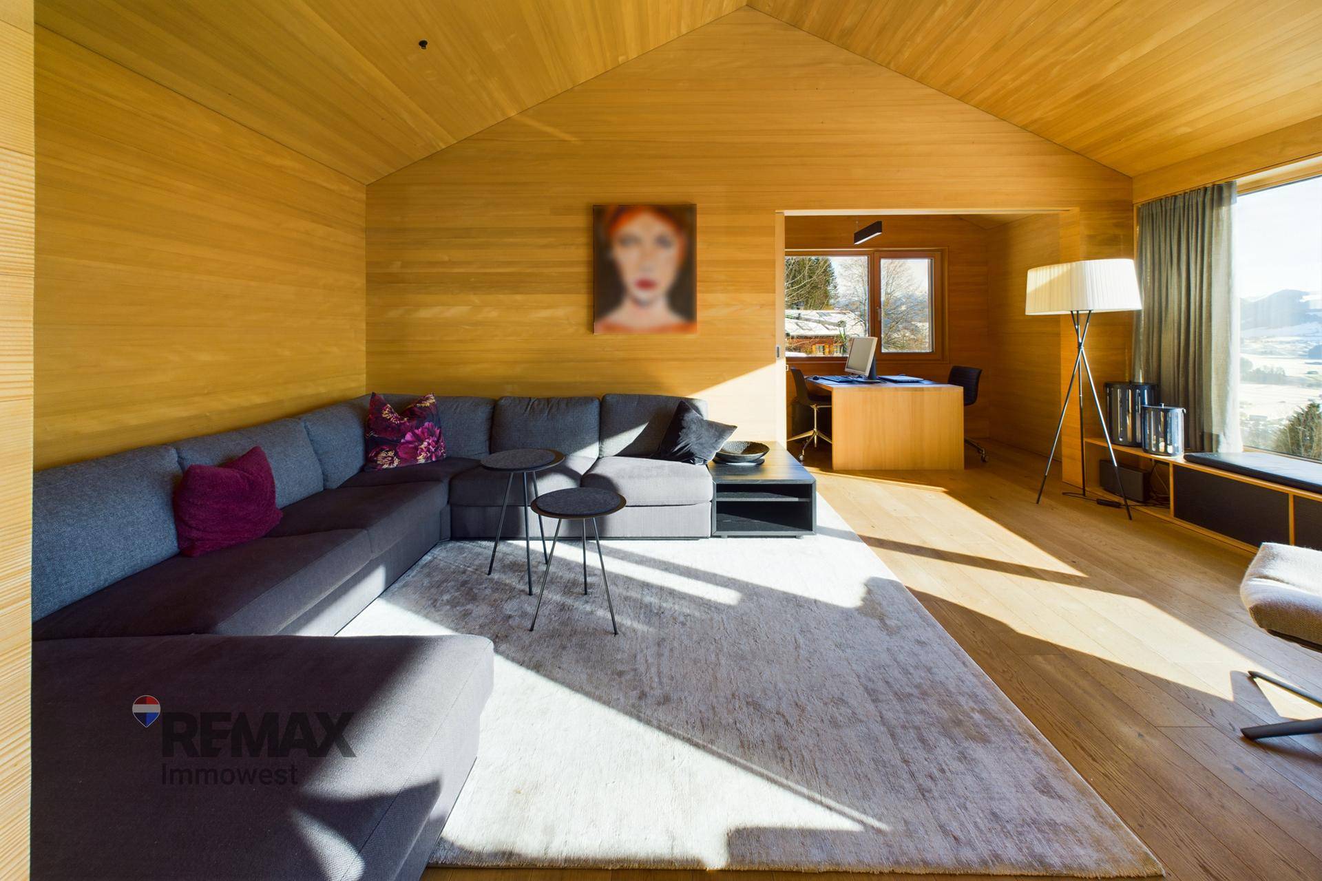 Gemütliches Wohnzimmer mit großem Sofa, Holzwänden und integriertem Arbeitsbereich.