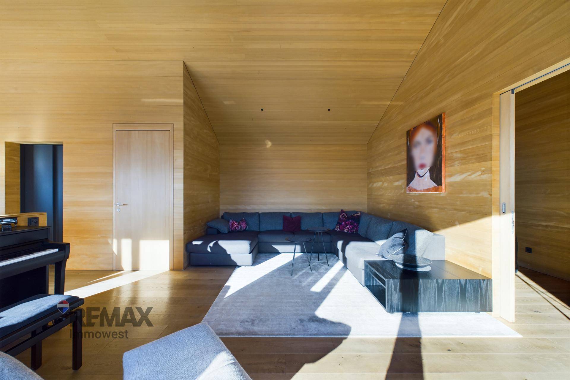 Modernes Wohnzimmer mit großem Ecksofa, Holzwänden und viel natürlichem Licht.