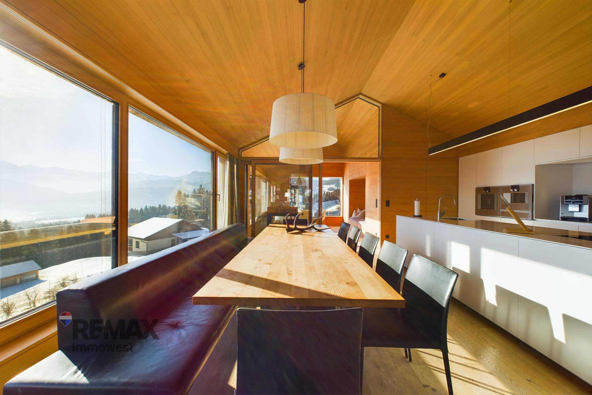 Geräumiger Essbereich mit Holztisch, Sitzbank und Panoramafenstern mit Bergblick.