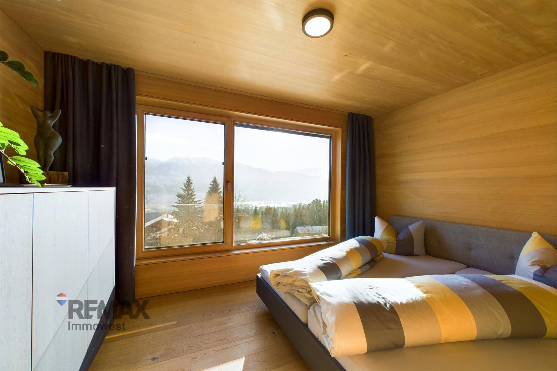 Schlafzimmer mit Bergblick, Holzwänden und großem Fenster für viel Tageslicht.
