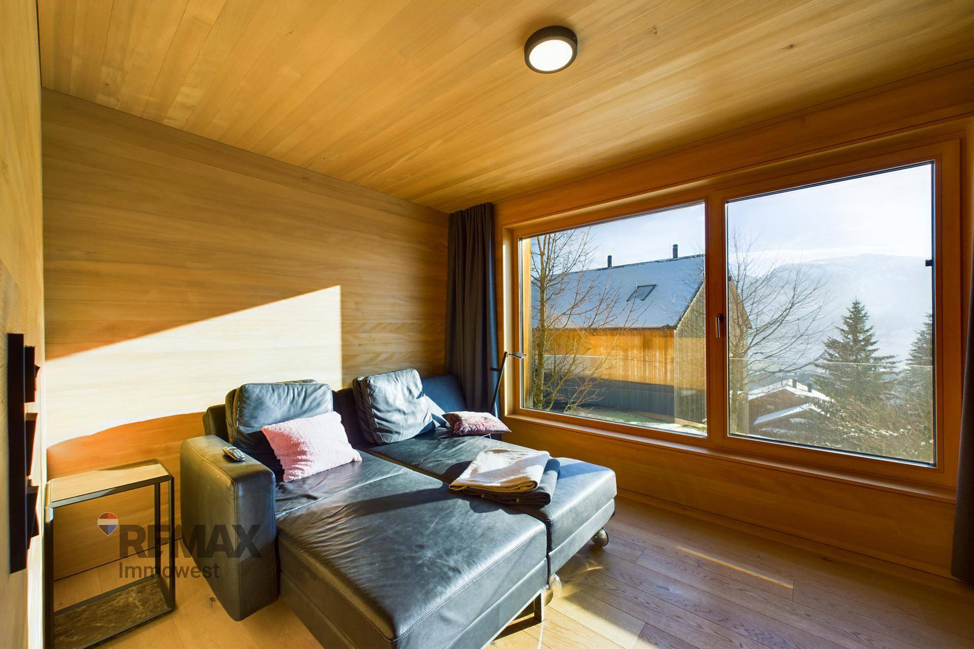 Gemütliches Schlafzimmer mit Liege und großem Fenster mit Blick auf die Umgebung.