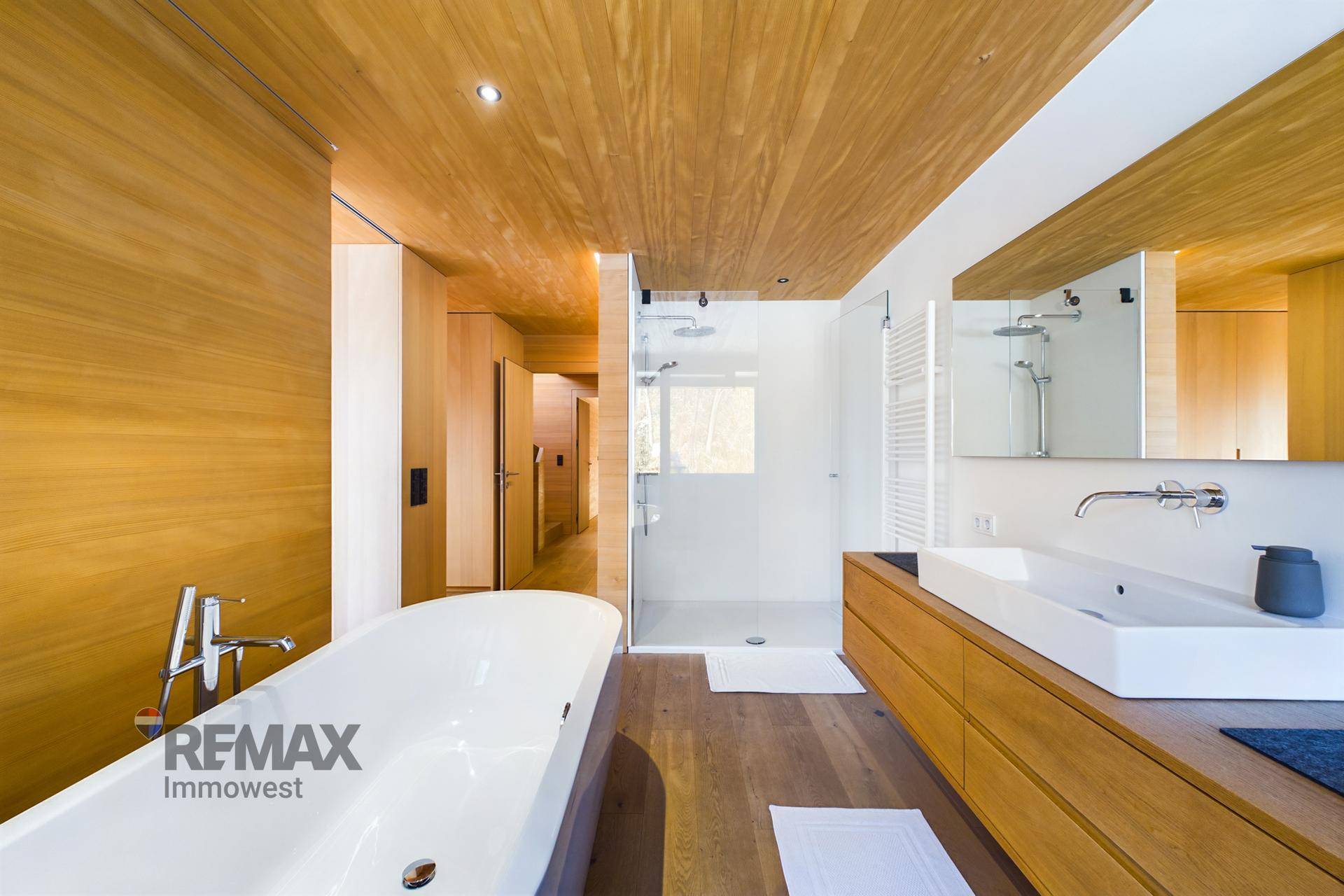 Elegantes Badezimmer mit freistehender Badewanne, begehbarer Dusche und Holzwaschtisch.