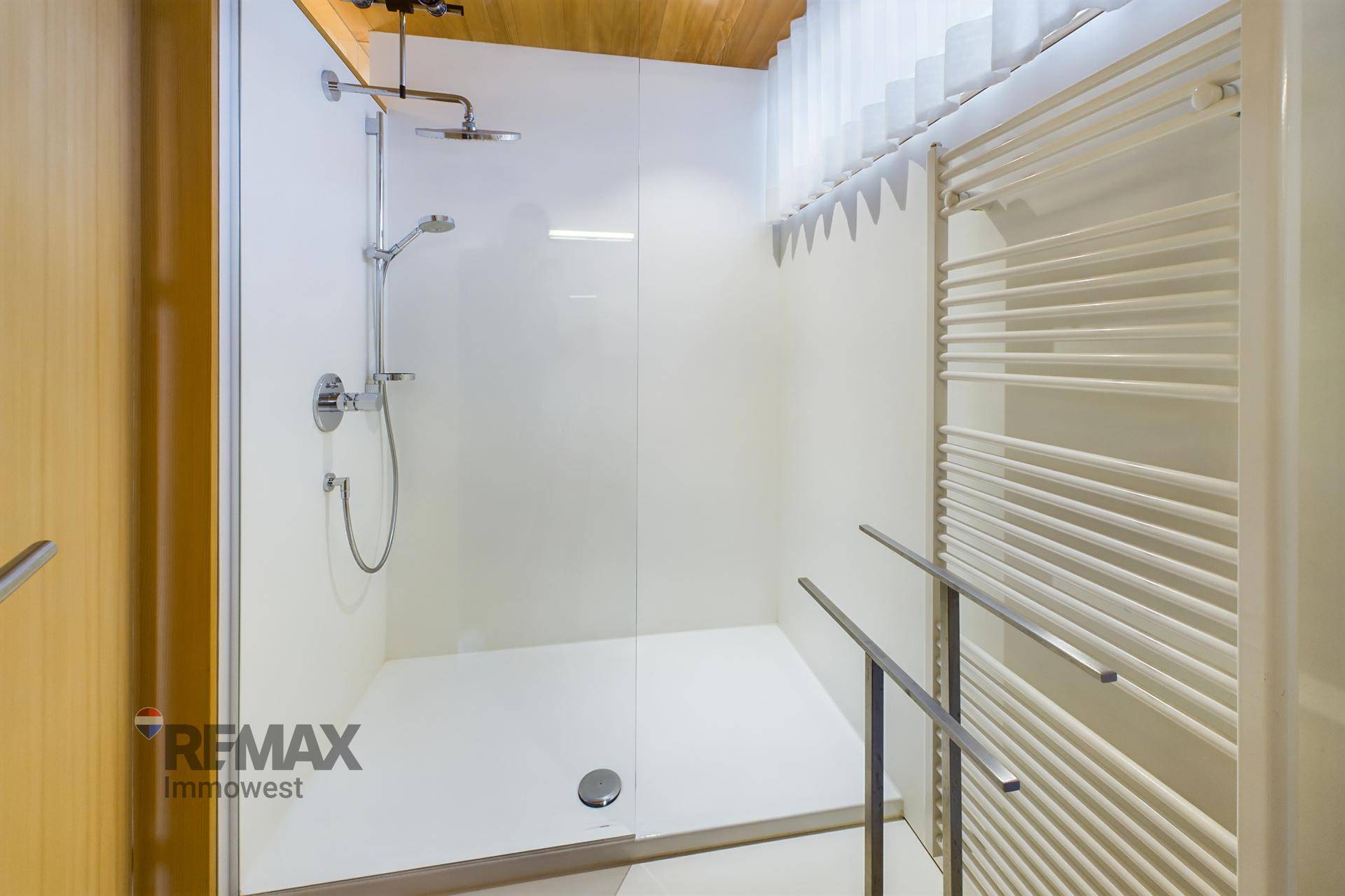 Moderne begehbare Dusche mit Regenduschkopf und beheiztem Handtuchhalter.