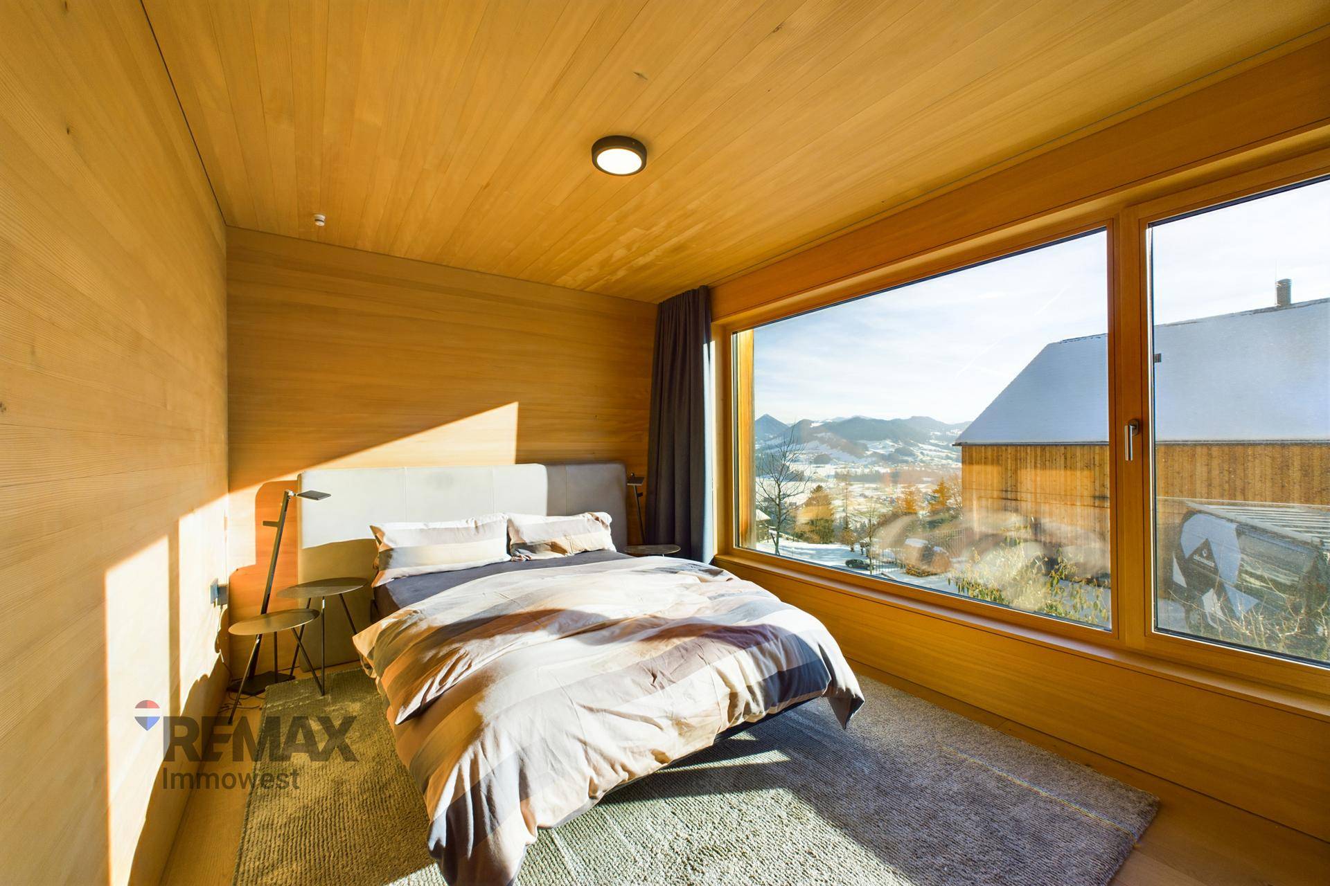 Schlafzimmer mit Doppelbett, Teppich und großem Fenster mit Blick auf die verschneite Landschaft.
