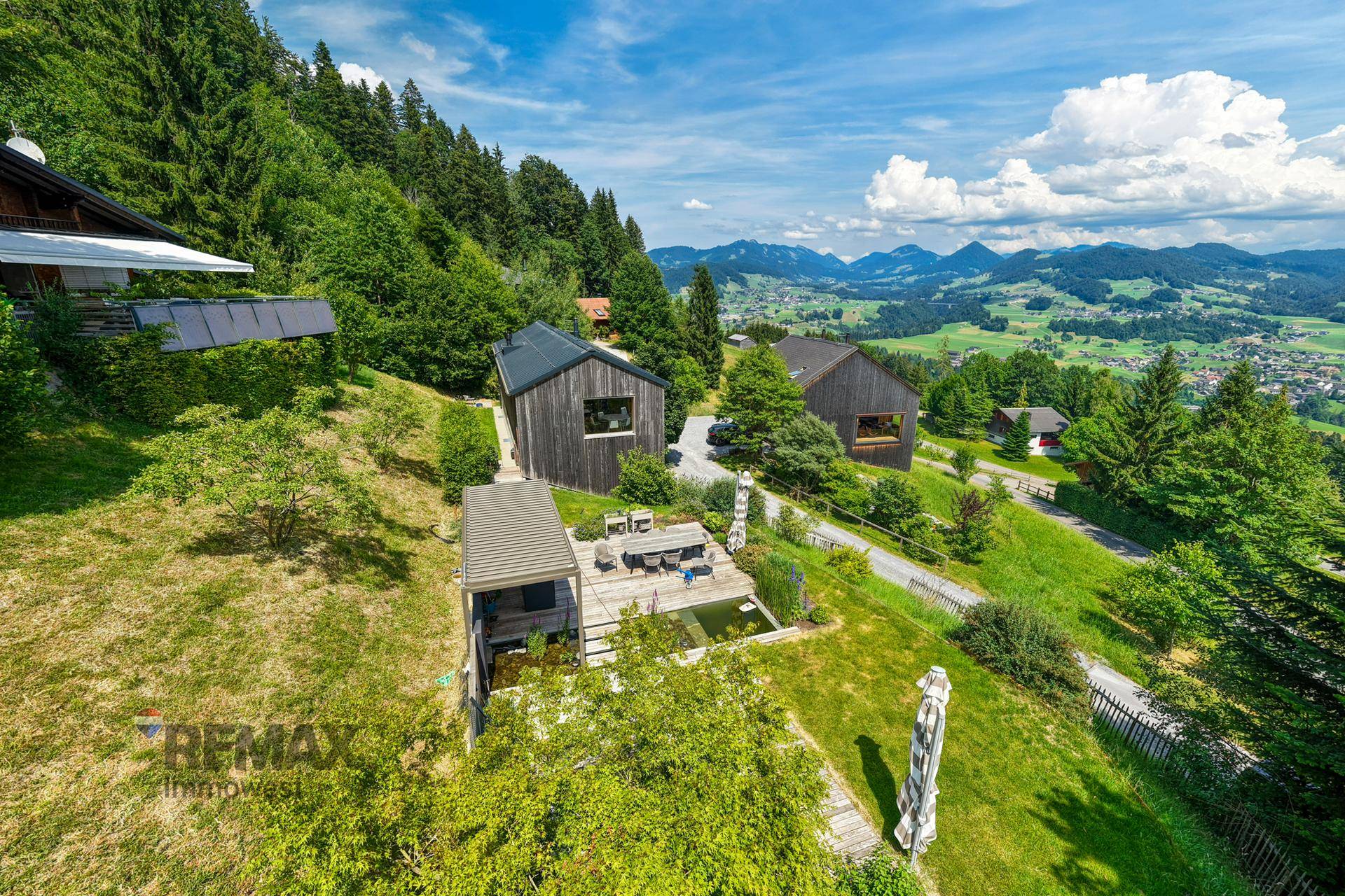 Große Terrasse mit Sitzgelegenheiten, Teich und atemberaubendem Panoramablick auf die Berge.