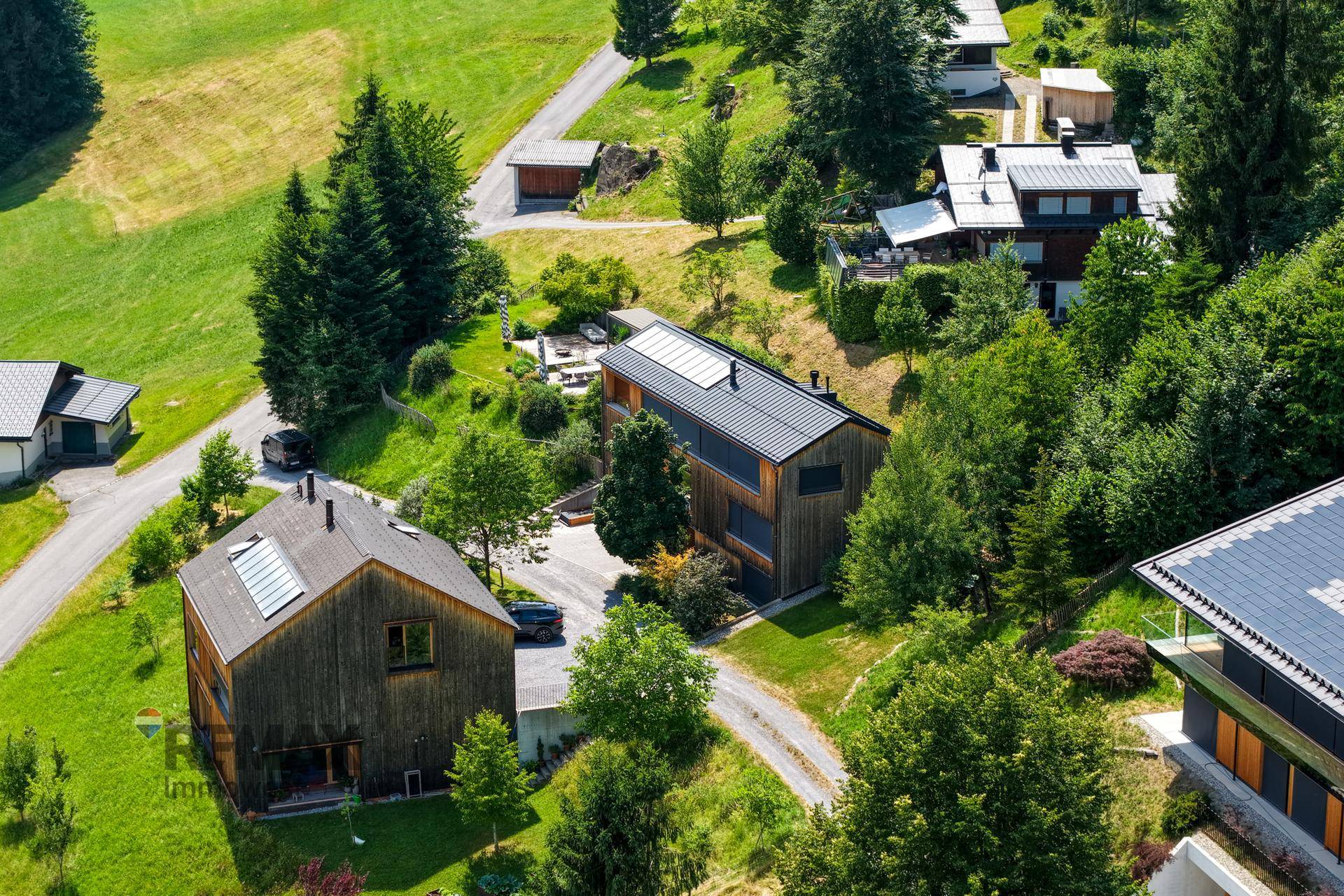 Weitläufige Luftaufnahme der modernen Häuser in der grünen Hügellandschaft.