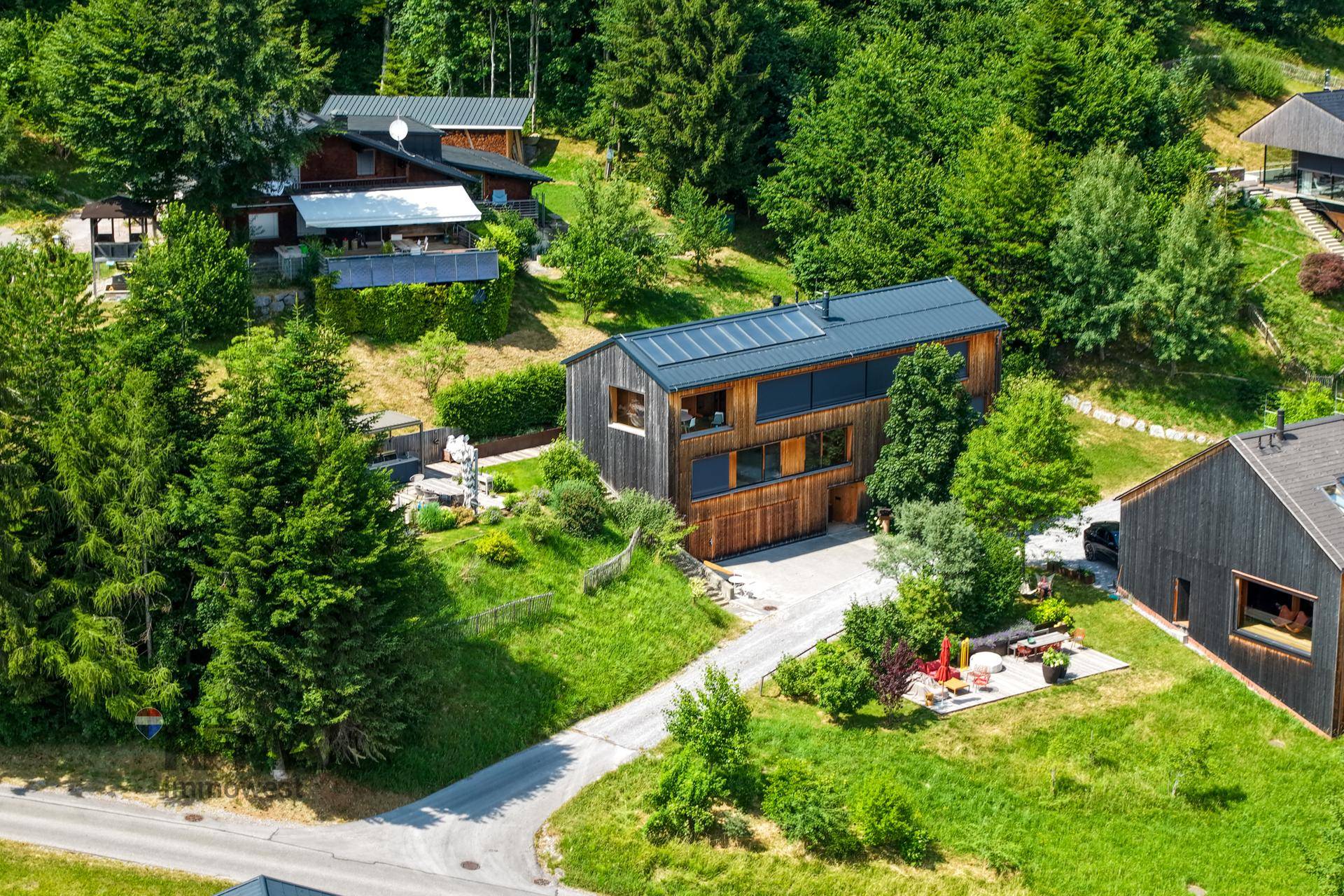 Luftaufnahme des modernen Holzhauses in idyllischer grüner Umgebung.