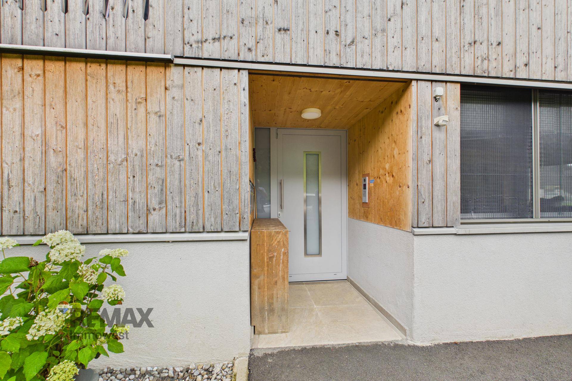 Eingangsbereich eines modernen Holzhauses mit heller Tür und schlichtem Design.