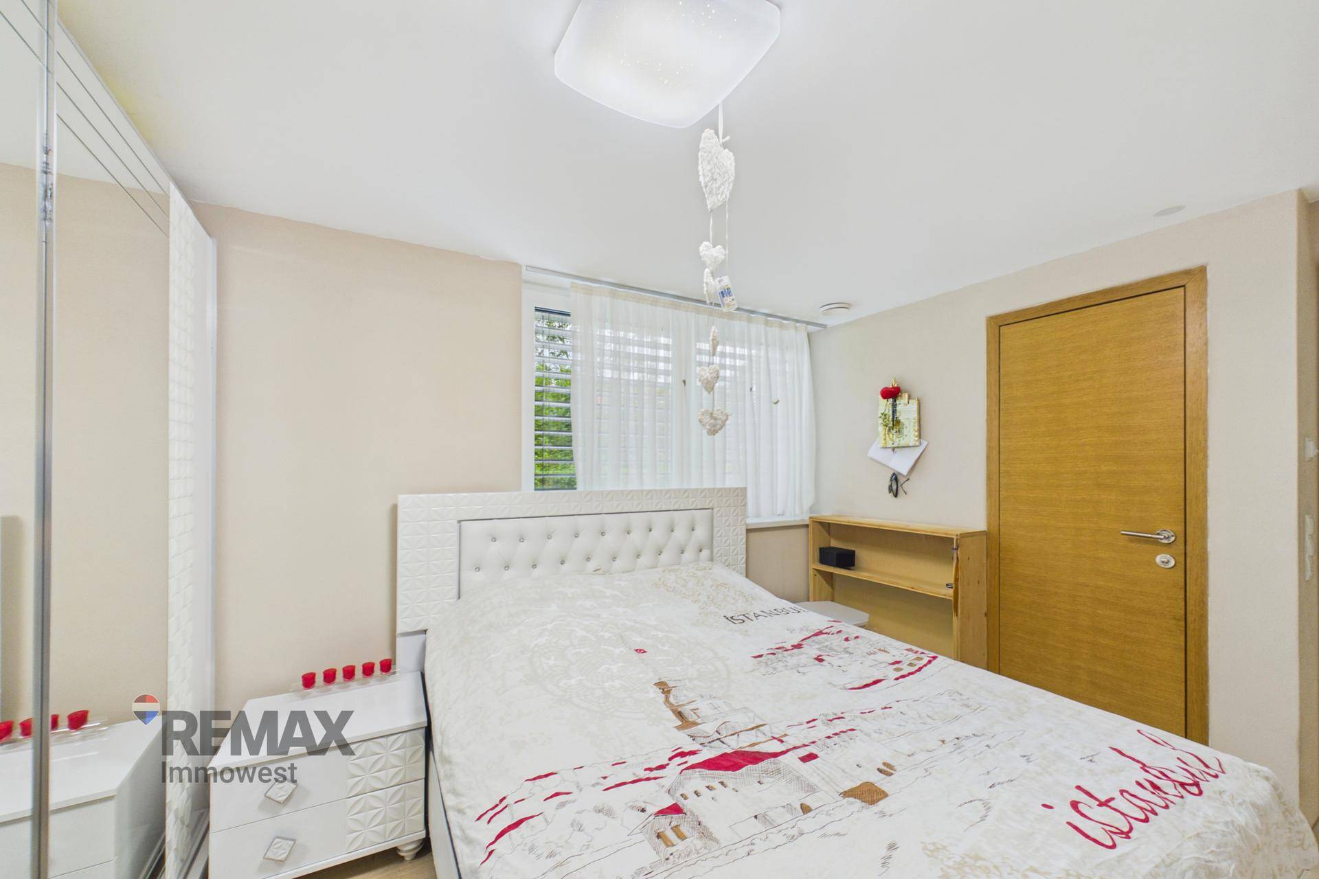 Helles Schlafzimmer mit Doppelbett, Nachttischen und Fenster mit Blick ins Grüne.