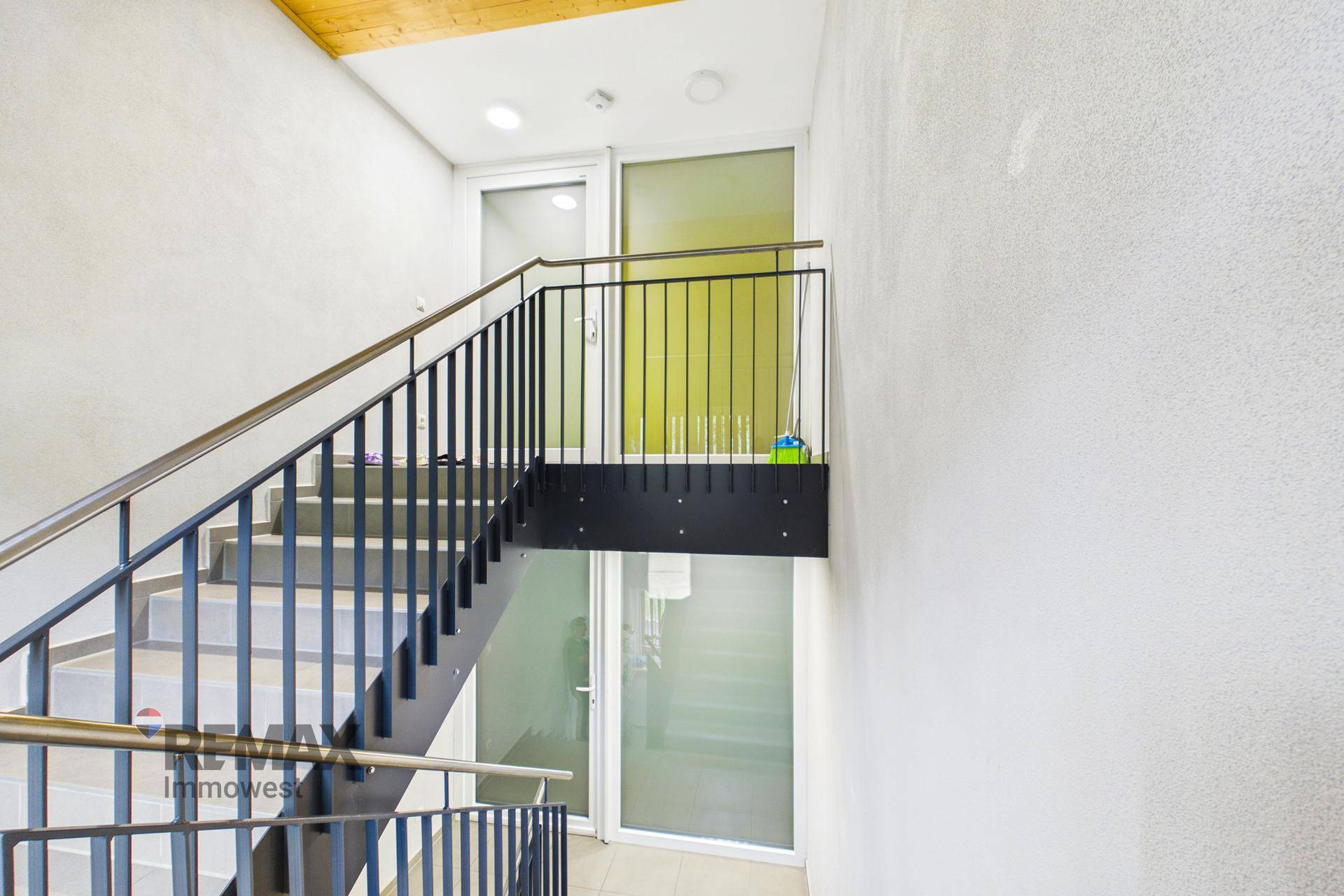Treppenhaus mit Metallgeländer und Blick auf den Eingangsbereich.