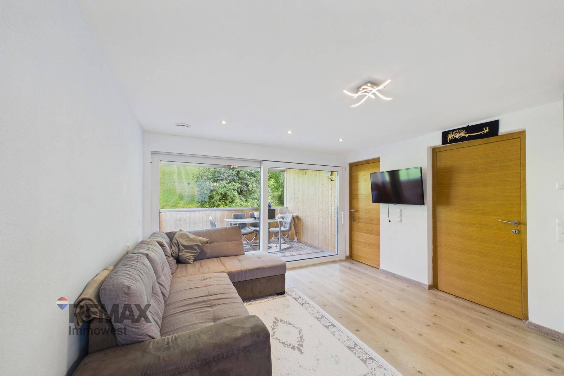 Gemütliches Wohnzimmer mit großem Sofa und Zugang zum Balkon.
