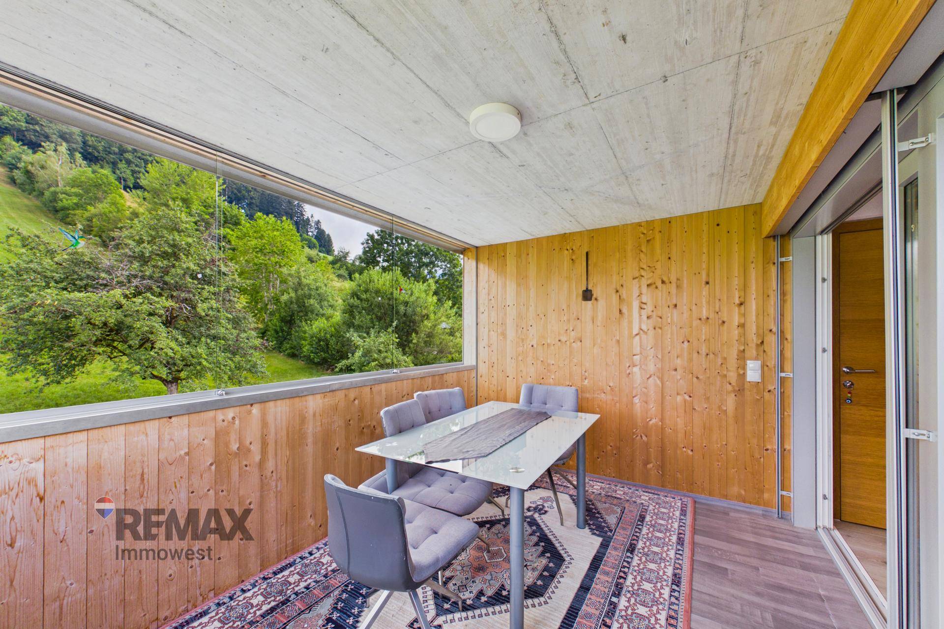 Verglaste Loggia mit Holzwänden und Esstisch, ideal für Mahlzeiten im Freien.