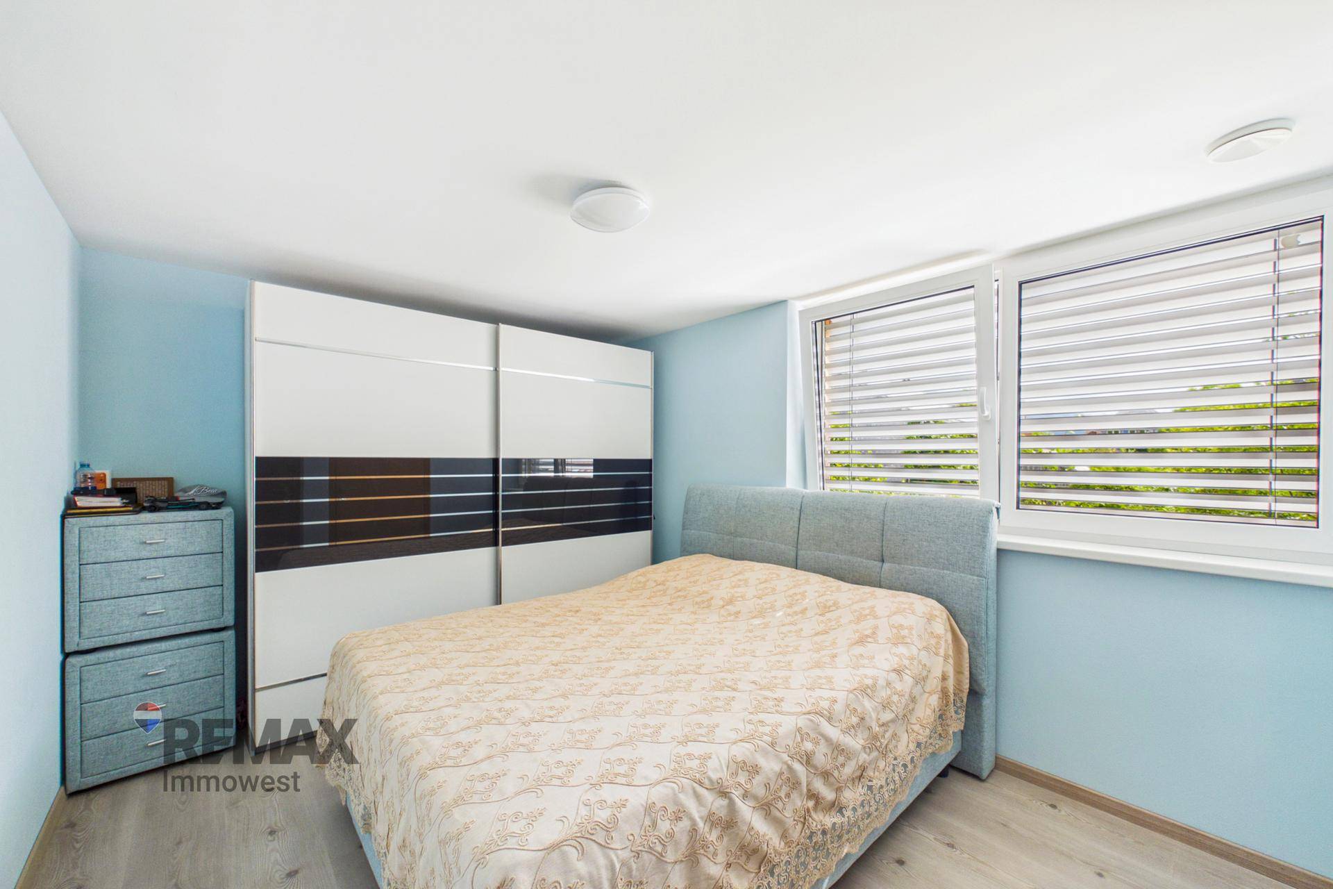 Schlafzimmer mit blauen Wänden, Schiebetürenschrank und Doppelbett.