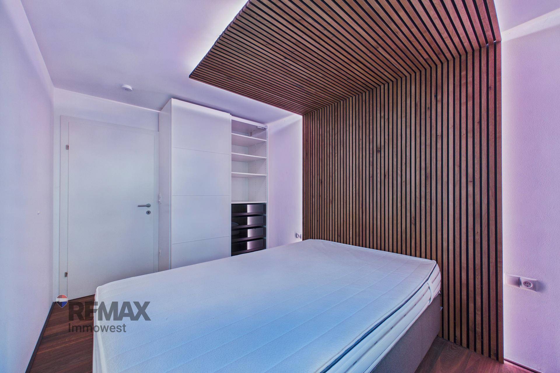 Schlafzimmer mit integriertem Kleiderschrank, Holzwandelementen und komfortablem Bett.