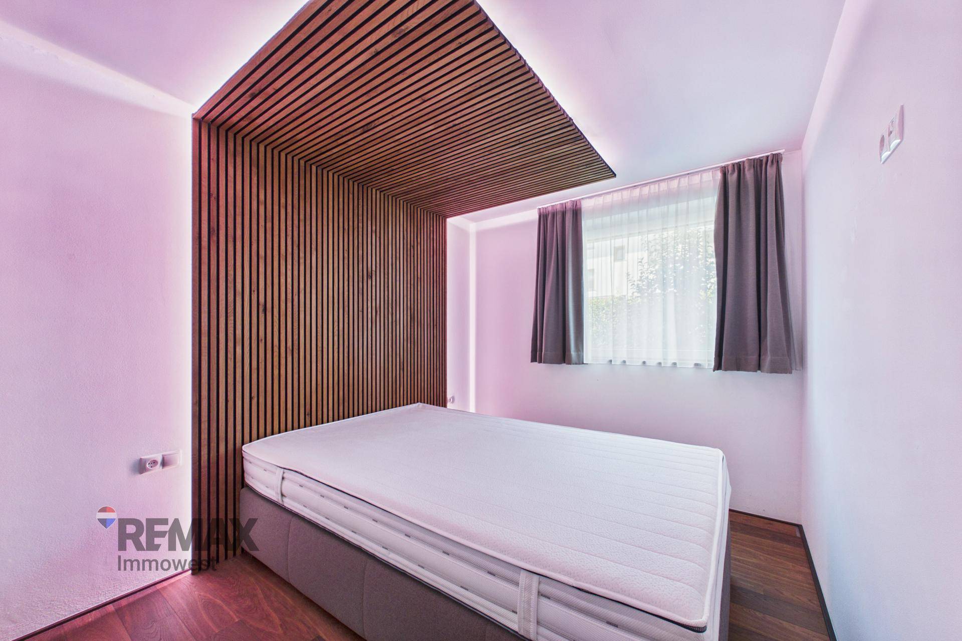Modernes Schlafzimmer mit Holzwandverkleidung, indirekter Beleuchtung und großem Fenster.