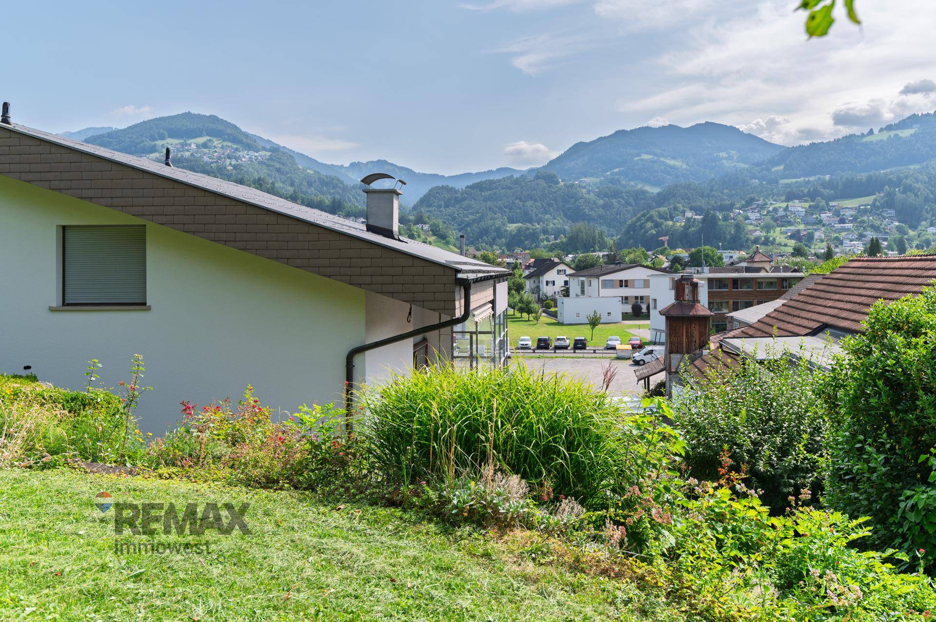 Gartenbereich mit Rasen und Sträuchern, bietet einen weiten Blick auf die umliegende Landschaft und Berge.