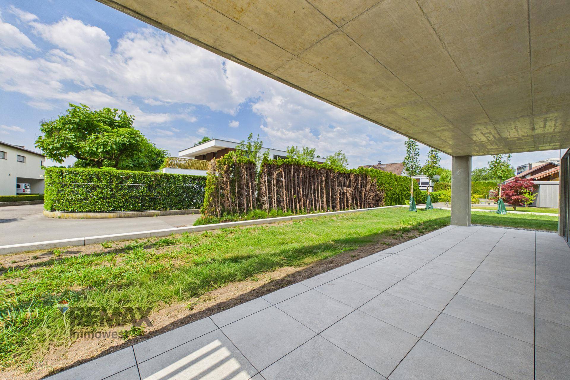 Große, geflieste Terrasse mit Blick auf den Garten und die grüne Umgebung.