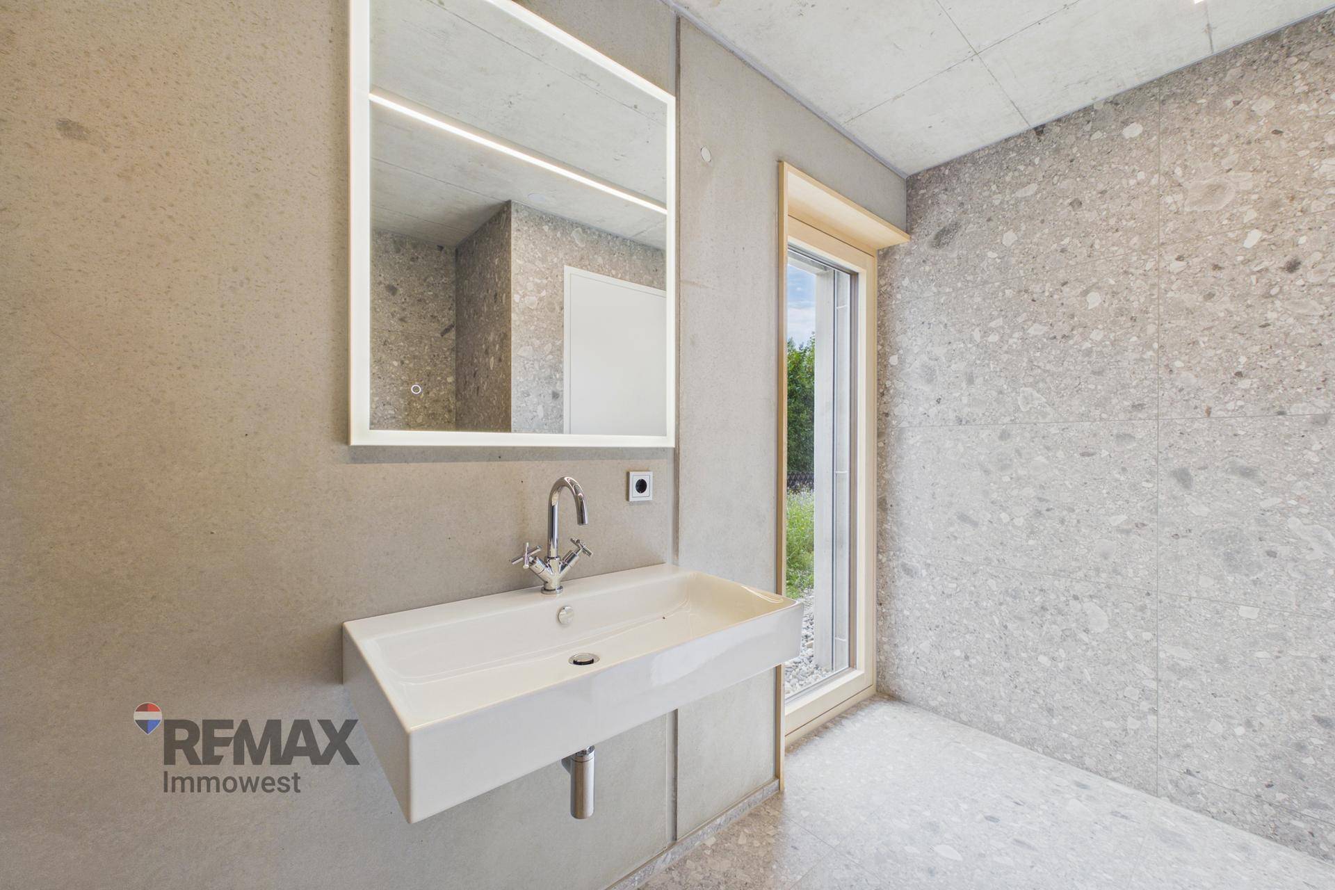Modernes Badezimmer mit großem Spiegel, Waschbecken und Fenster zum Garten.