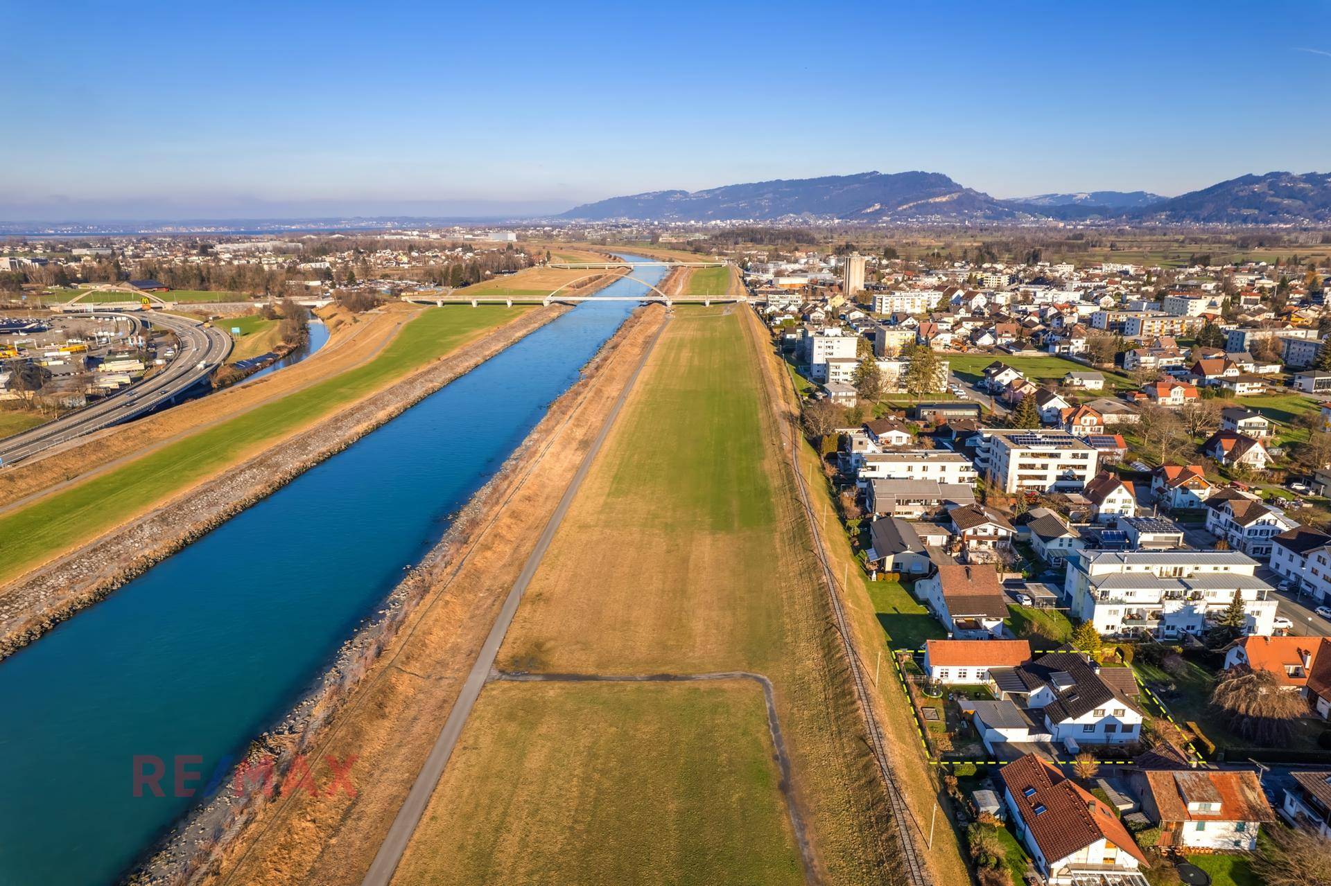 Panoramablick aus der Luft auf eine Wohngegend neben einem Fluss oder Kanal und weiten Feldern.