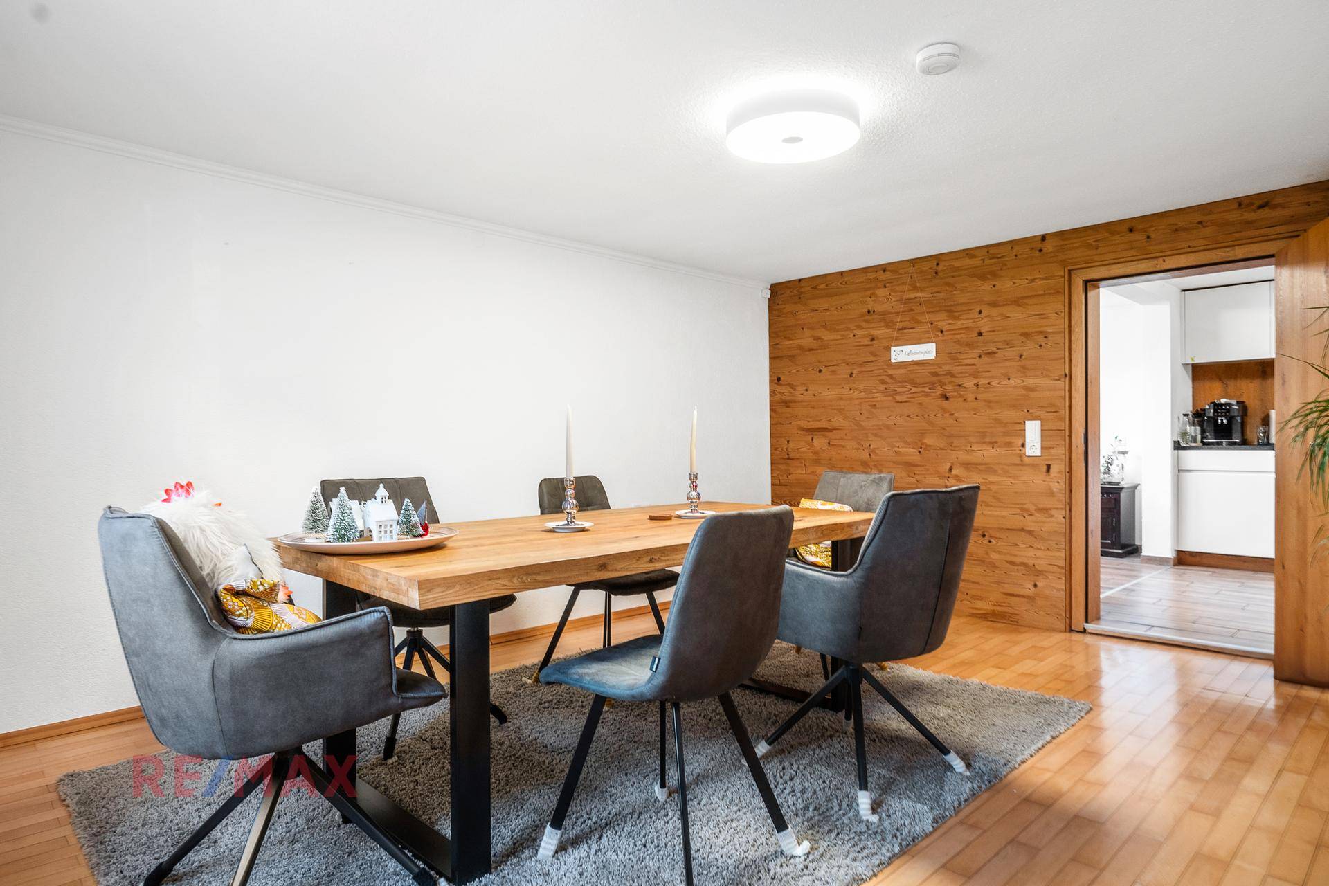 Gemütlicher Essbereich mit Holztisch, modernen Stühlen und einer Holzwandverkleidung.