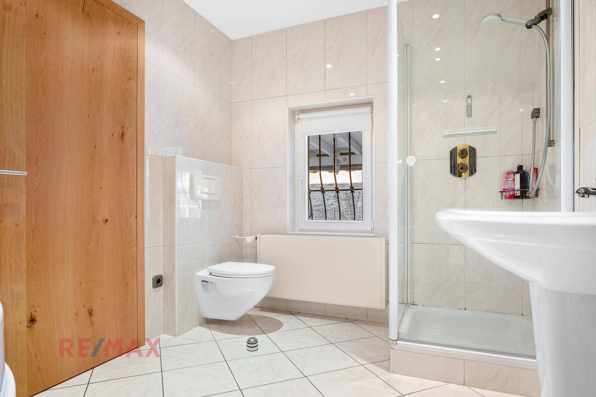 Helles Badezimmer mit Duschkabine, wandhängendem WC und Fenster.