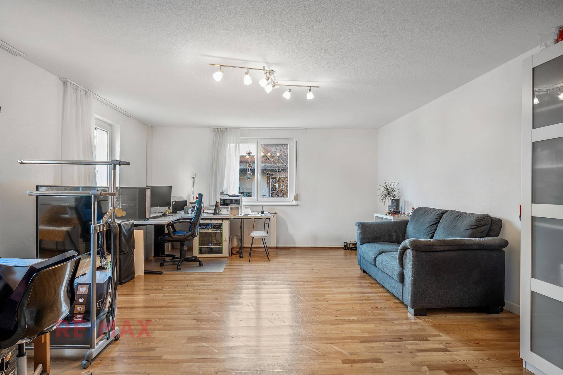 Geräumiges Wohnzimmer, das auch als Büro genutzt wird, mit Holzfußboden und Sofa.