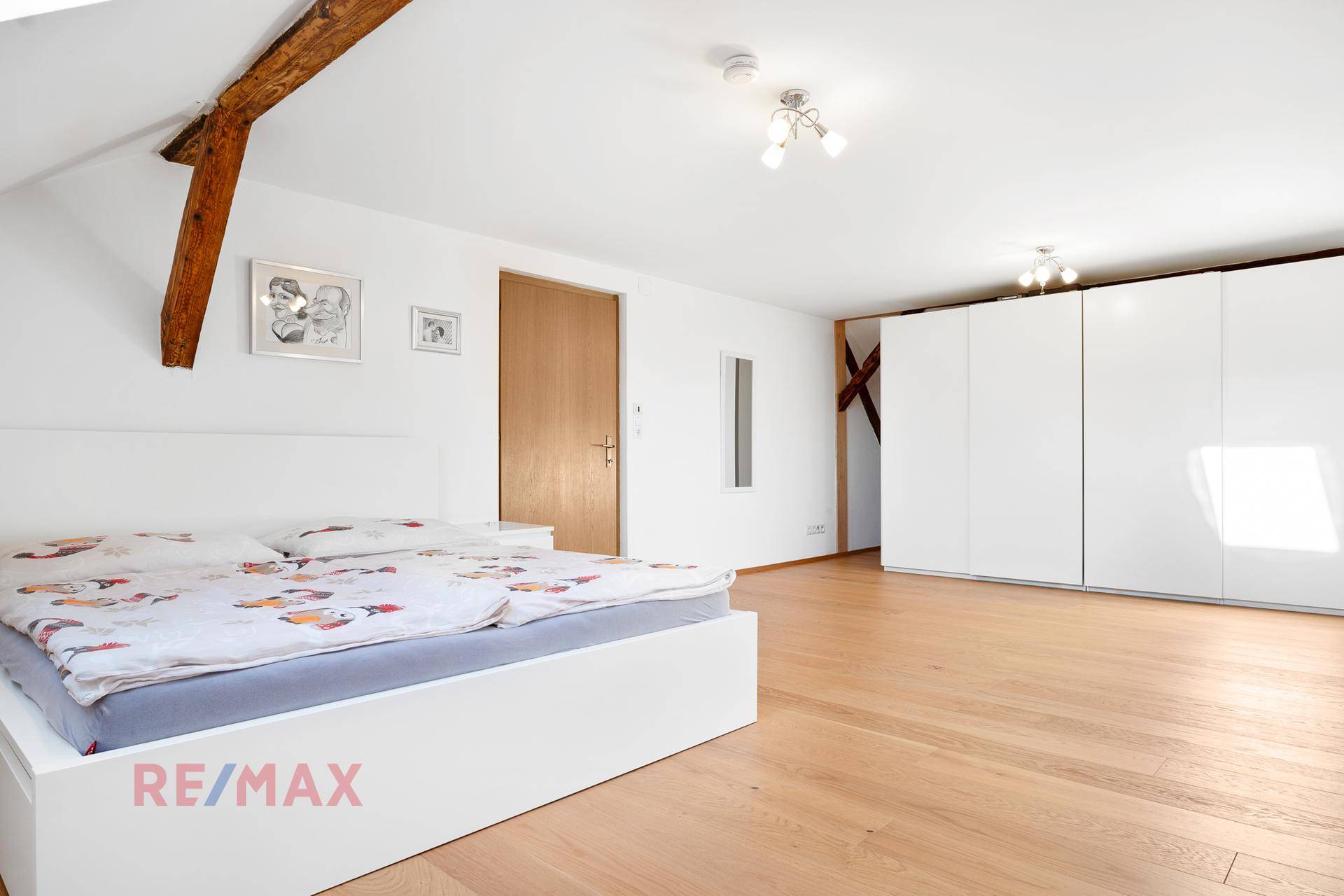 Geräumiges Schlafzimmer mit Holzboden, weißem Bett und großen Einbauschränken.