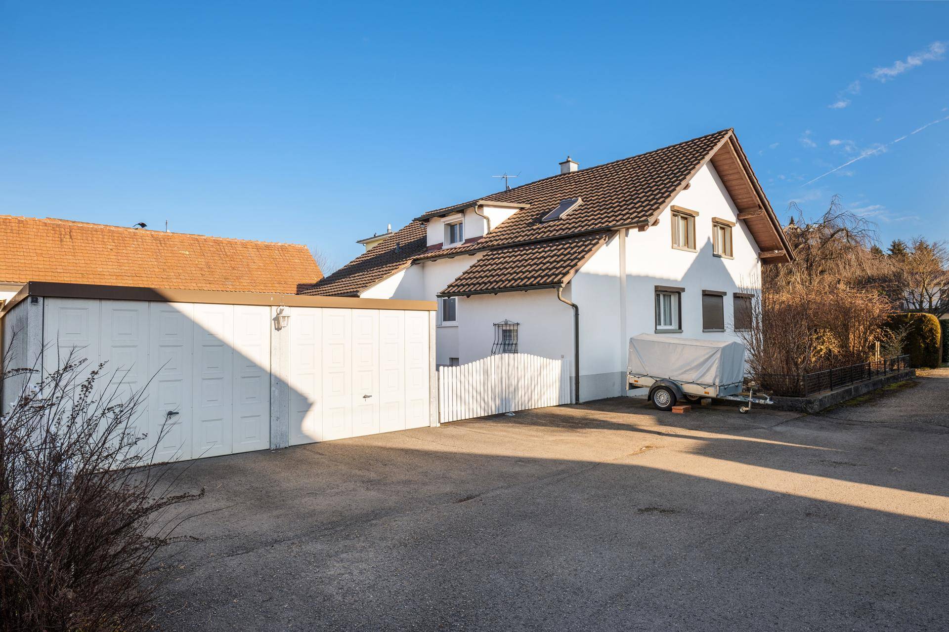 Doppelgarage mit Zufahrt und einem Anhänger auf dem Grundstück.