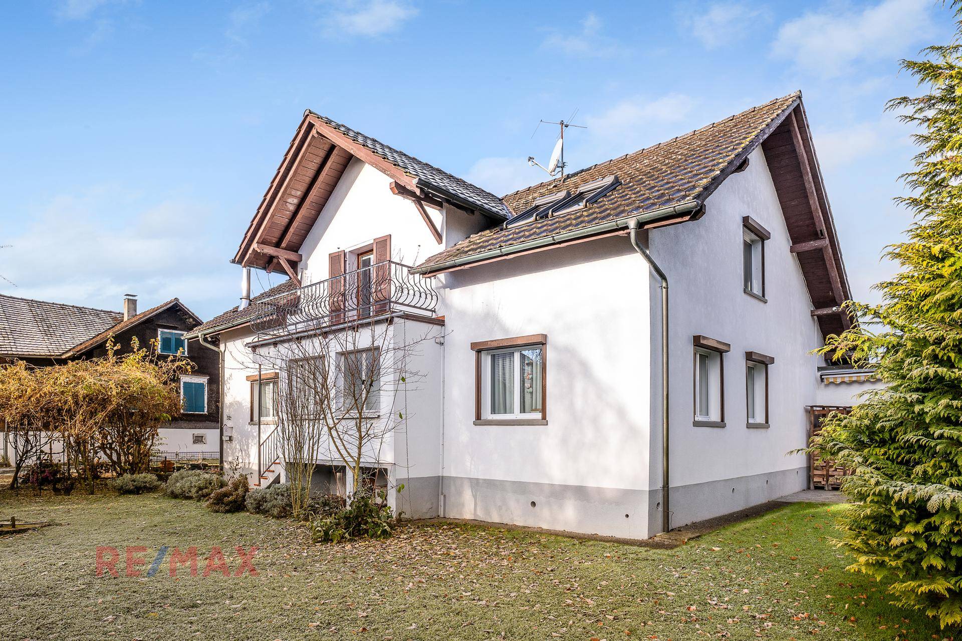 Seitenansicht des Hauses mit Garten, Balkon und gepflegter Rasenfläche.