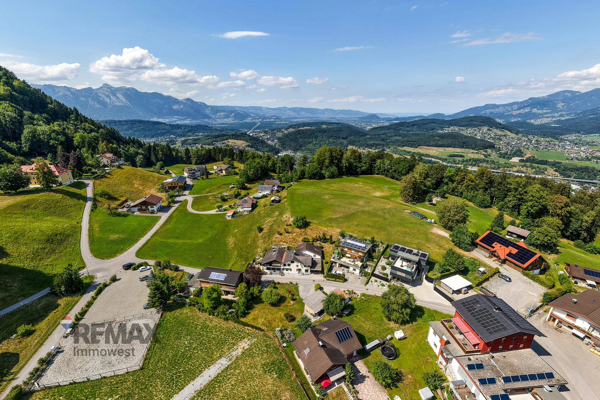 Panoramablick über eine ausgedehnte grüne Landschaft mit verstreuten Häusern und einem weiten Tal.