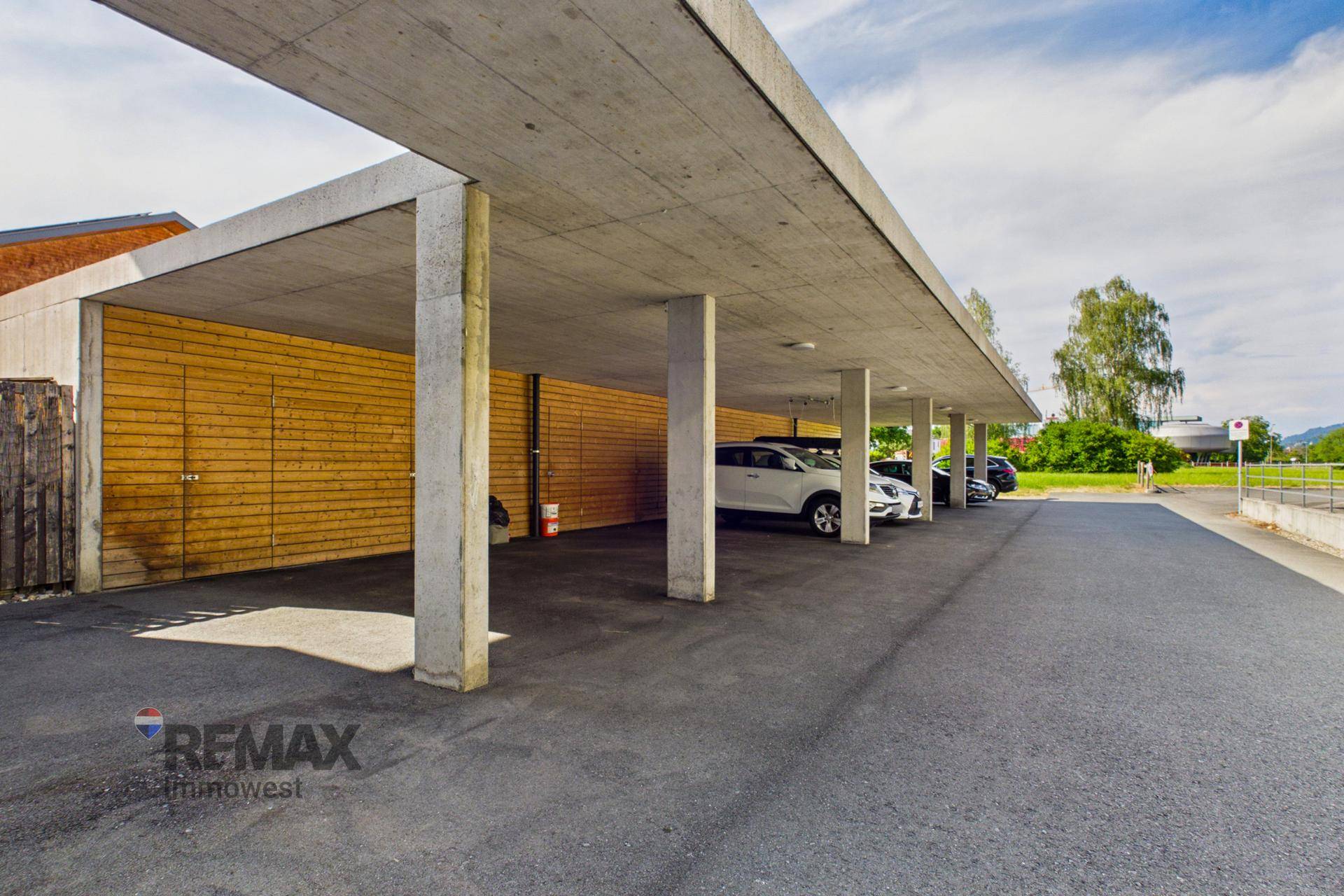 Überdachter Parkplatz (Carport) mit mehreren Stellplätzen und Betonkonstruktion.