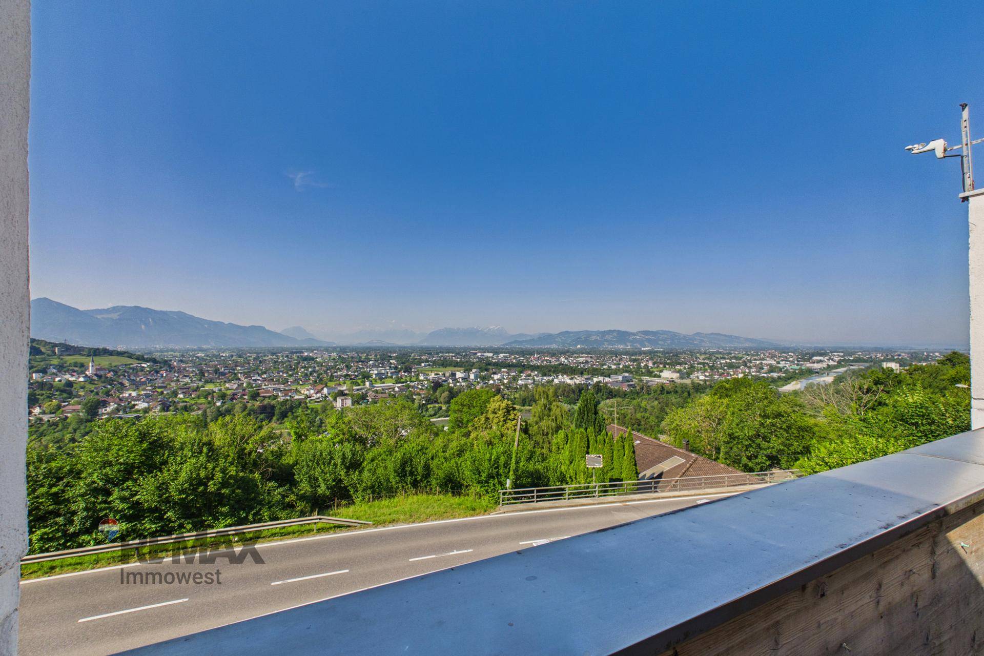Atemberaubender Ausblick von der Terrasse auf die Stadt, eine Straße und die majestätischen Berge.