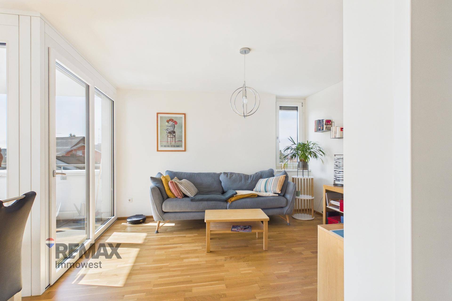 Helles Wohnzimmer mit großen Schiebetüren zum Balkon, Holzfußboden und modernem Sofa.