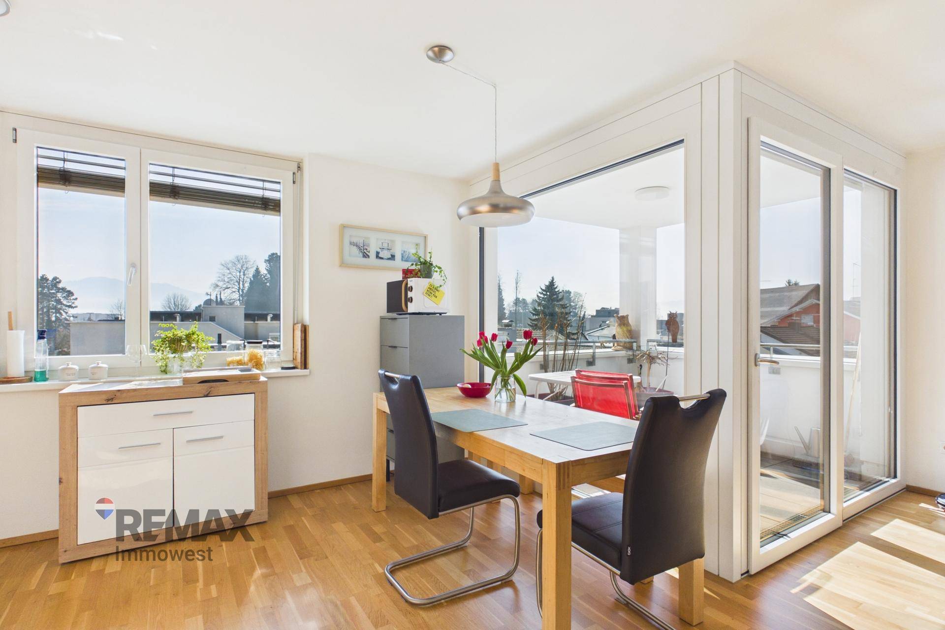 Heller Essbereich mit Holztisch, Stühlen und großen Fenstern mit Zugang zum Balkon.