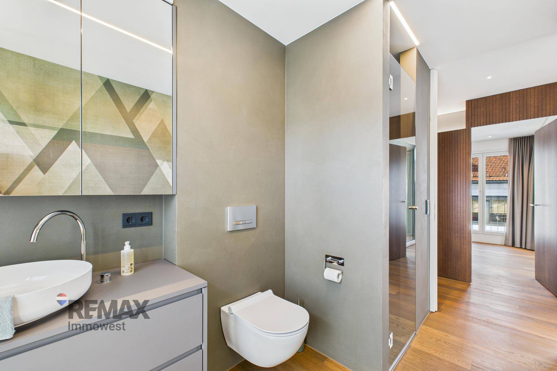 Modernes Gäste-WC mit wandhängender Toilette, Waschbecken und Spiegelschrank.