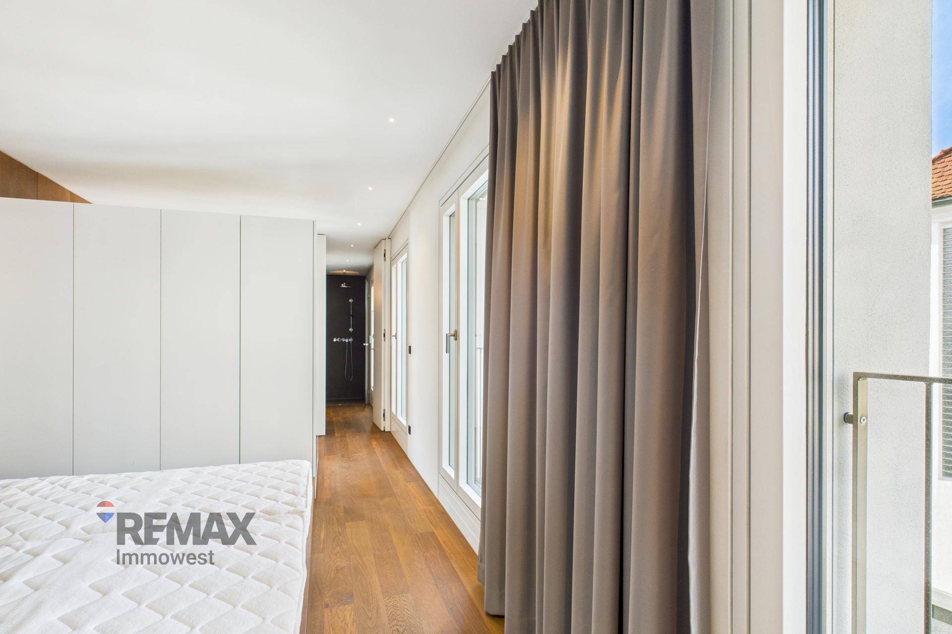 Helles Schlafzimmer mit Holzboden, Einbauschränken und Zugang zu einem französischen Balkon.