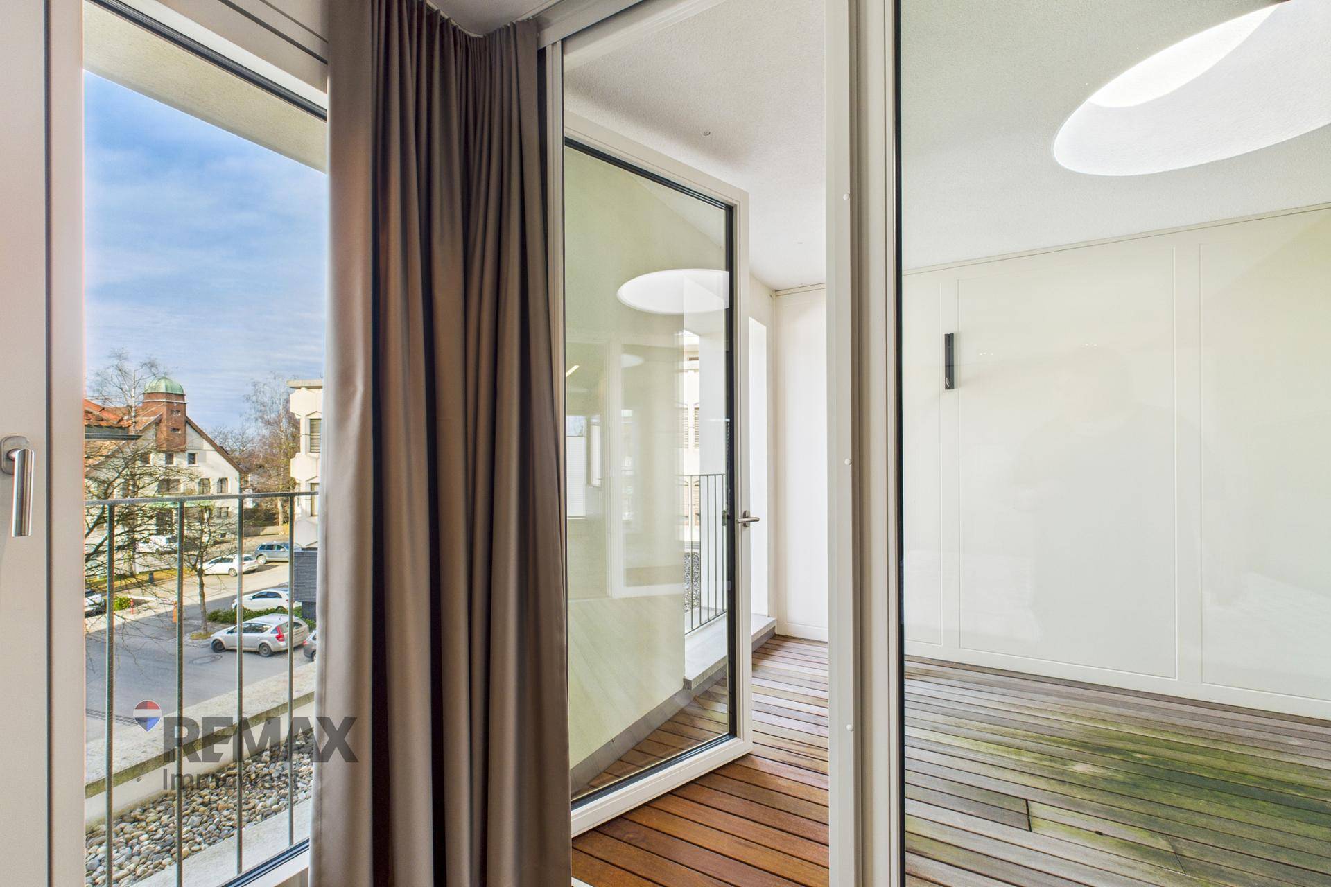 Heller Raum mit Holzboden und Zugang zu einem französischen Balkon mit Stadtblick.